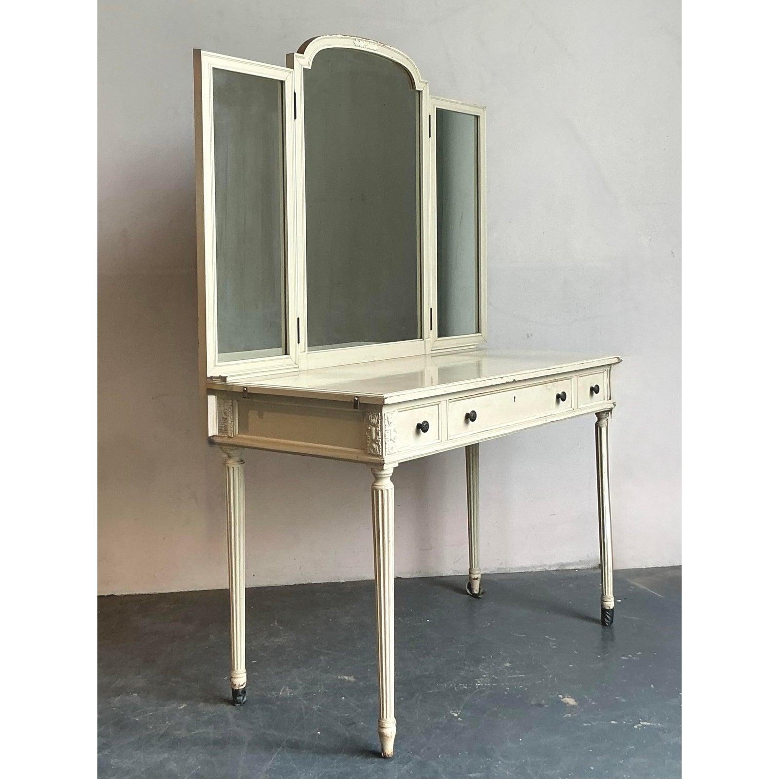 Presenting a beautiful Vintage Regency Irving and Casson vanity, a testament to the elegant and refined style of the mid-20th century. This piece, with its classic painted wood finish, features a striking triple-pane mirror that adds both beauty and