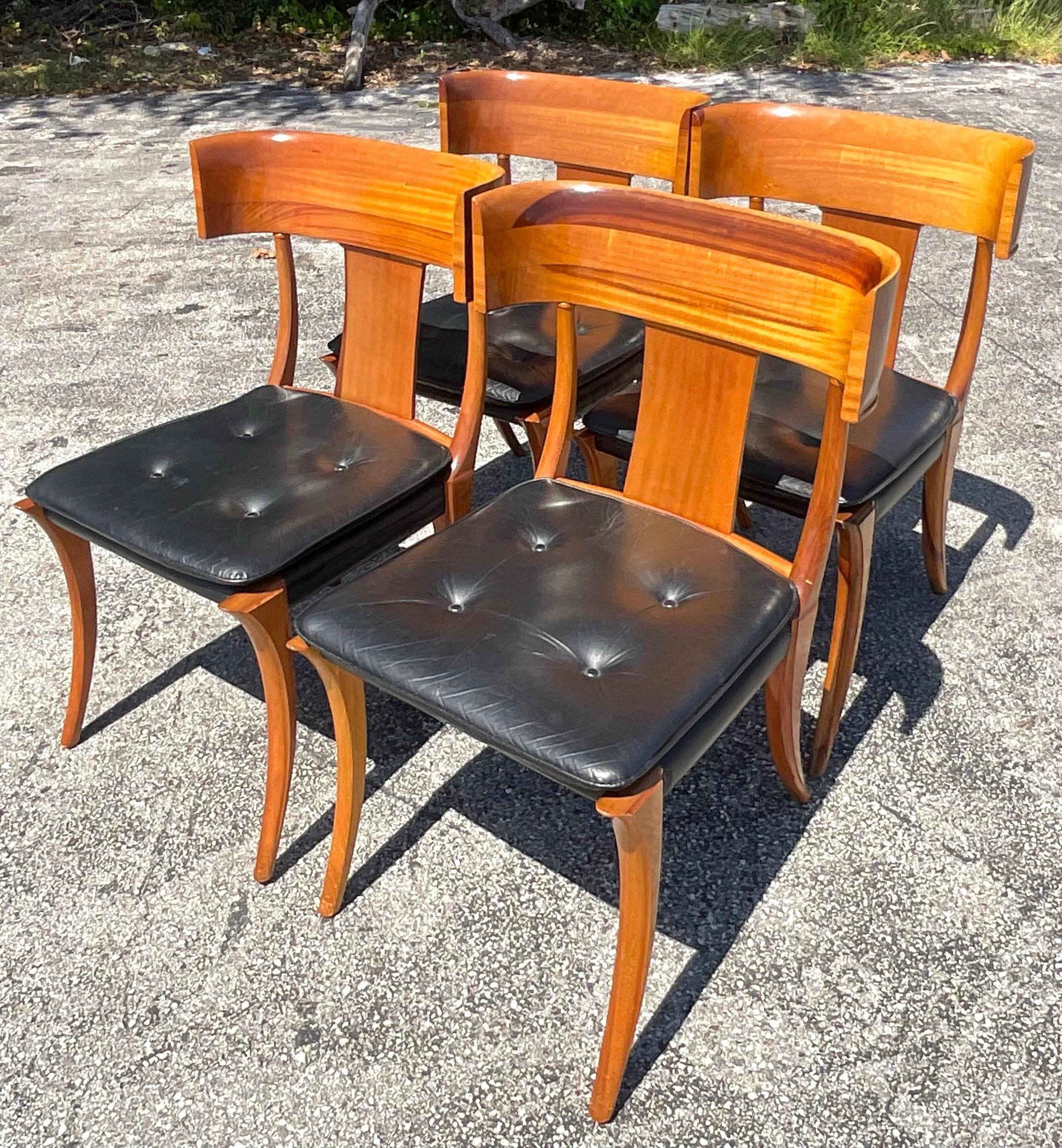 An extraordinary set of four vintage Boho dining chairs. The classic Klismos shape done in the manner of Kipp Stuart. Brilliant wood grain detail and a beautiful patina from time to time tufted black leather seats and saber legs. Acquired from a