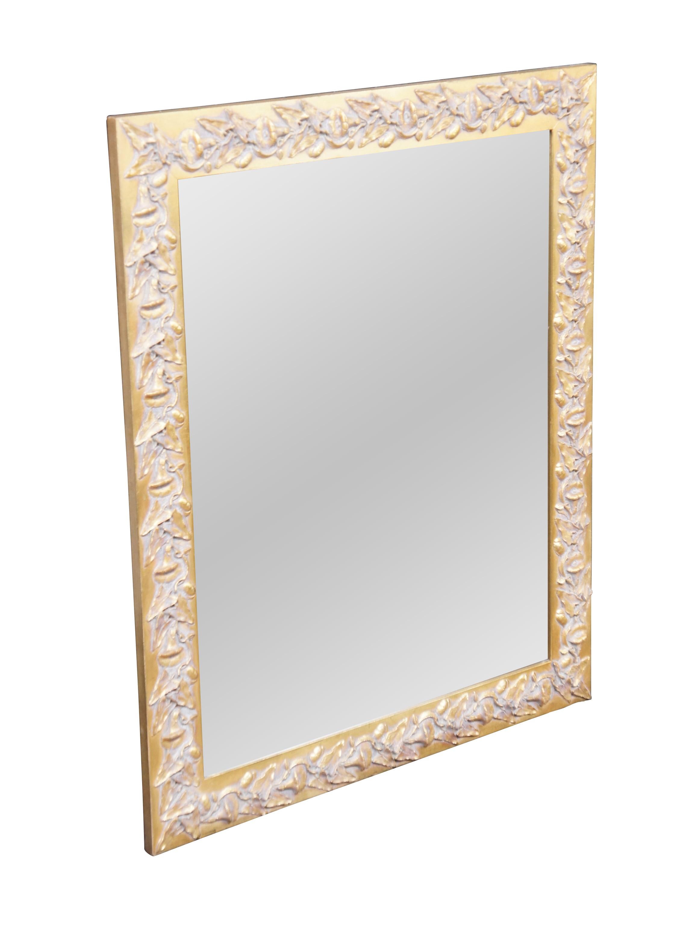 An ornate Neoclassical style mirror from the last half of the 20th century.  Features a low relief raised frame with foliate and vine motif.  The mirror can be used horizontal or vertical.  Great for use in along any wall, in a bathroom or as an
