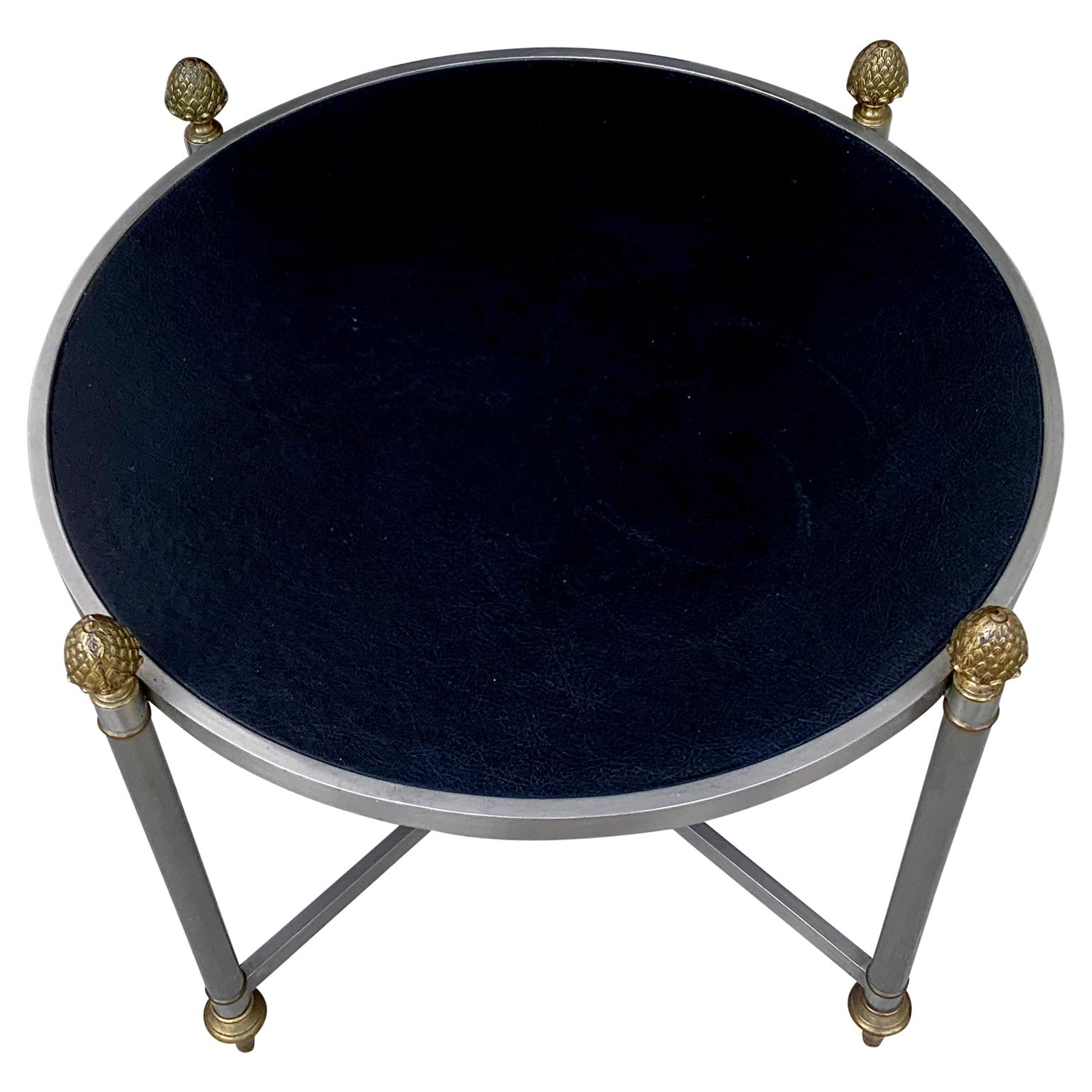 A vintage neoclassical Maison Jansen cocktail table. Classic design with brass pinecone finials, brushed steel and black leatherette top.