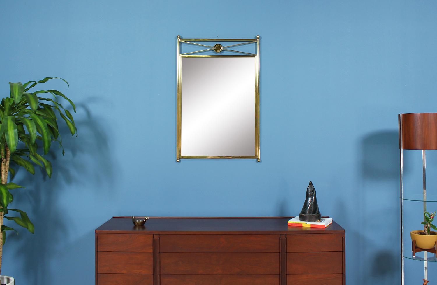 Dazzling mirror designed and manufactured by Baker Furniture Co. in the United States circa 1950’s. This beautiful Neoclassical style mirror features a sturdy lightly patinated brass-plated frame and maintains its original mirror creating a look of