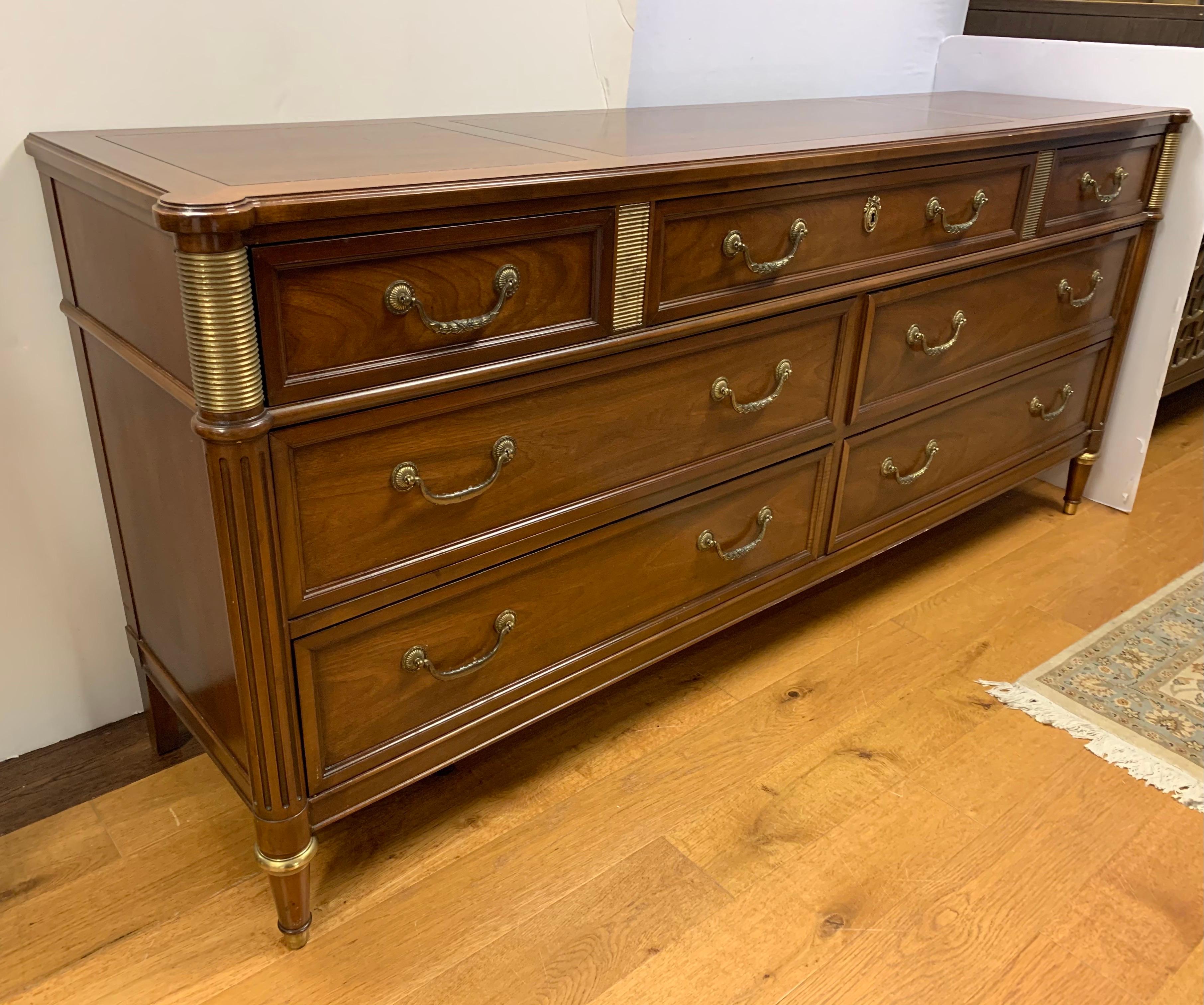 Neoclassical style seven drawer dresser with gilt and brass accents. By Baker Furniture.