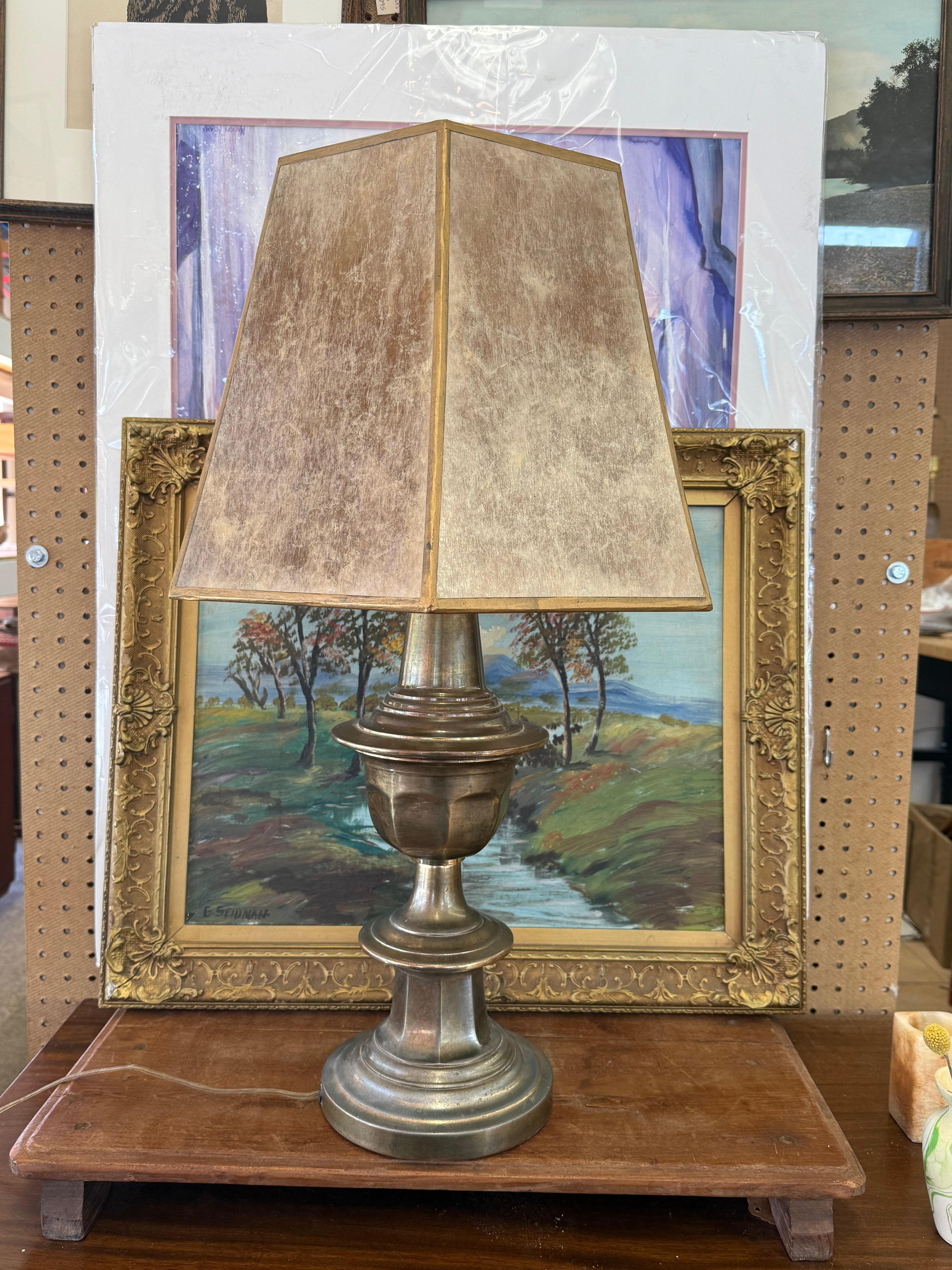  The lamp is in the Neoclassical style, characterized by its classical urn shape, symmetrical proportions, and polished metal finish. This style, inspired by ancient Greek and Roman designs, emphasizes clean lines and minimal ornamentation, popular