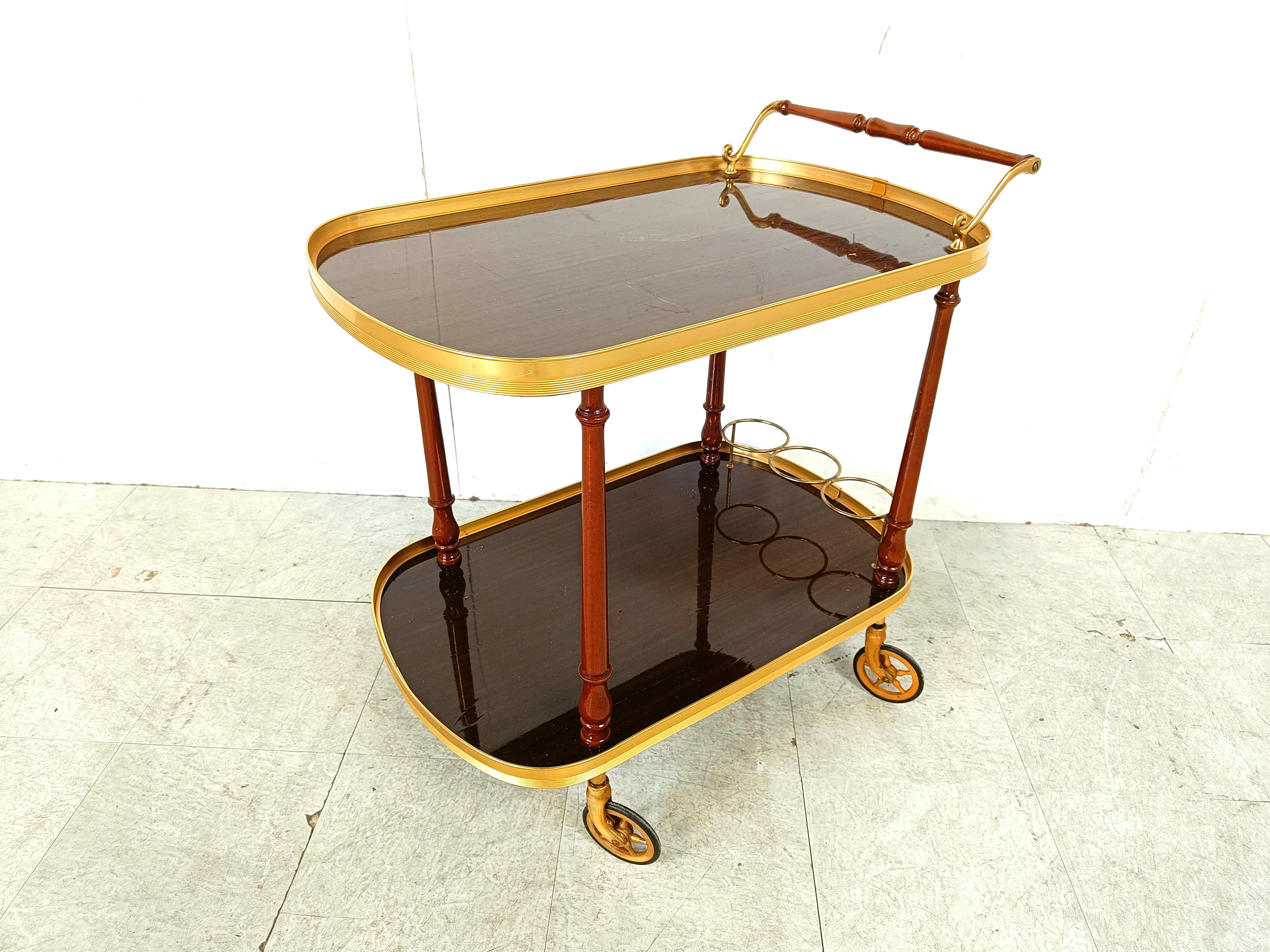 Elegant mid century neoclassical style serving trolley.

Beautiful brass details and two tiered veneer wooden trays.

Three bottle holders and enough space for glasses and other.

1960s- France

Good condition with normal age related