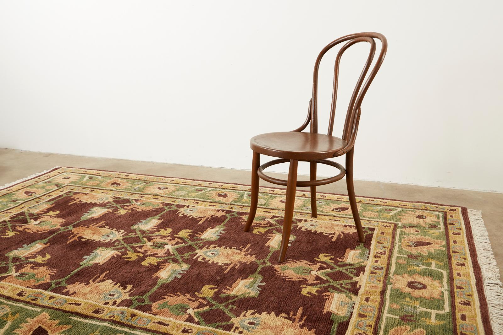 Unique wool rug from Nepal featuring an Arts & Crafts style design. Gorgeous brown field with a warm aubergine tone is bordered by a moss green border. Stylized palmettes and flowers decorate the entire rug with earth tone highlights in a William