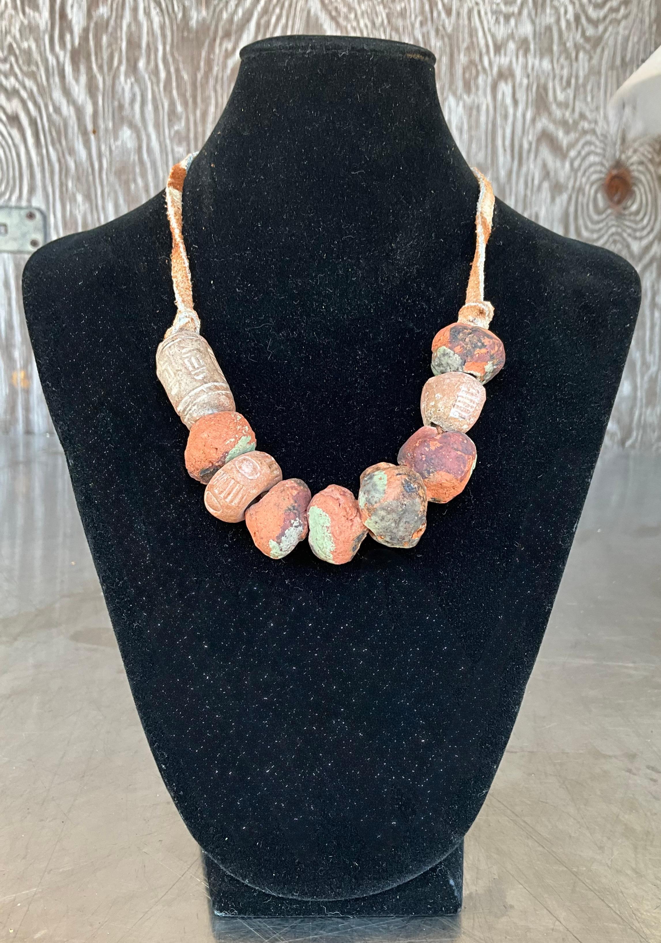 Questa collana vintage in terracotta nepalese con perline è un pezzo accattivante che riflette il ricco patrimonio culturale e l'arte tradizionale del Nepal. Realizzata a mano con argilla naturale di terracotta, ogni perlina viene modellata, cotta e