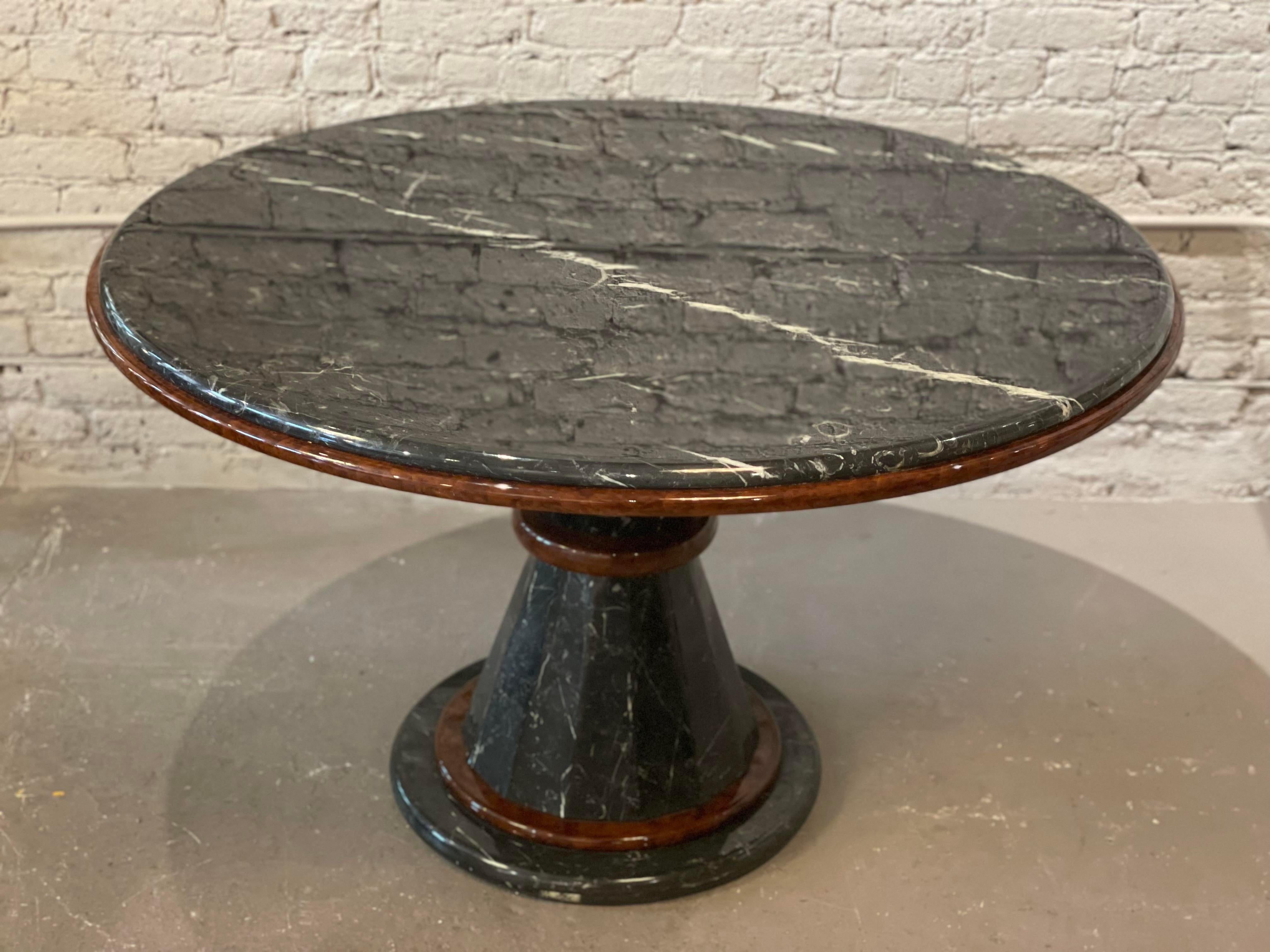 Beautiful table in excellent condition. The mahogany wood accents takes this classic marble table into a different sphere. The channeled base narrows at the center. Perfect for dining (4 to 5 chairs) or an entry table with huge flowers on it!
 