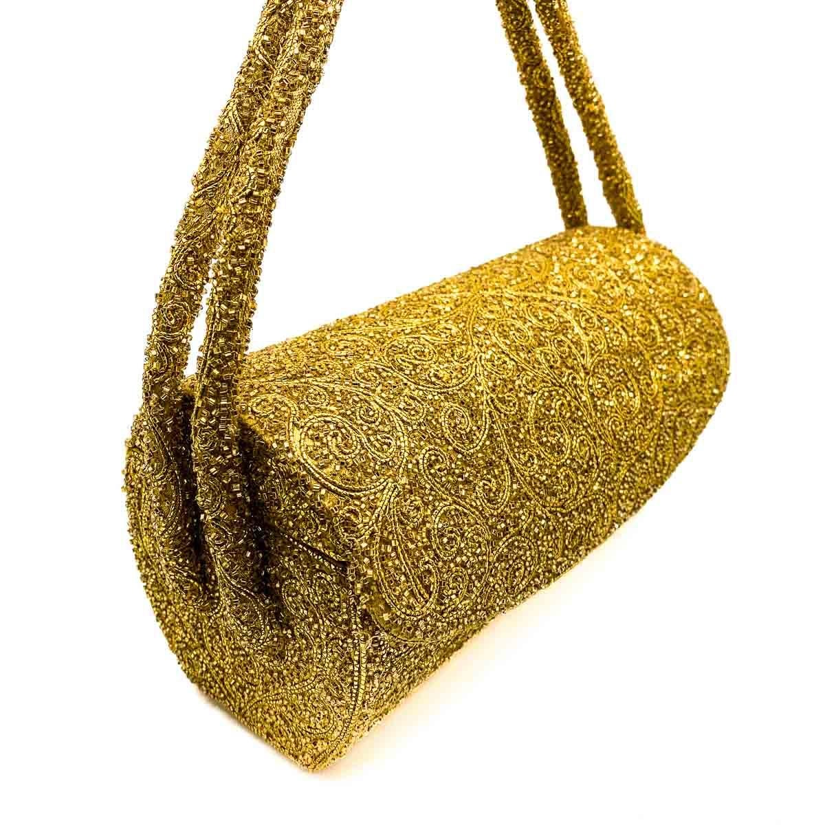 A fabulous and rare Vintage Nettie Rosenstein Evening Bag. A landscape cylinder inspired design is topped with a double handle and gloriously flaunts gold micro beading in a foliate design against a gold satin backdrop. The satin story continues to