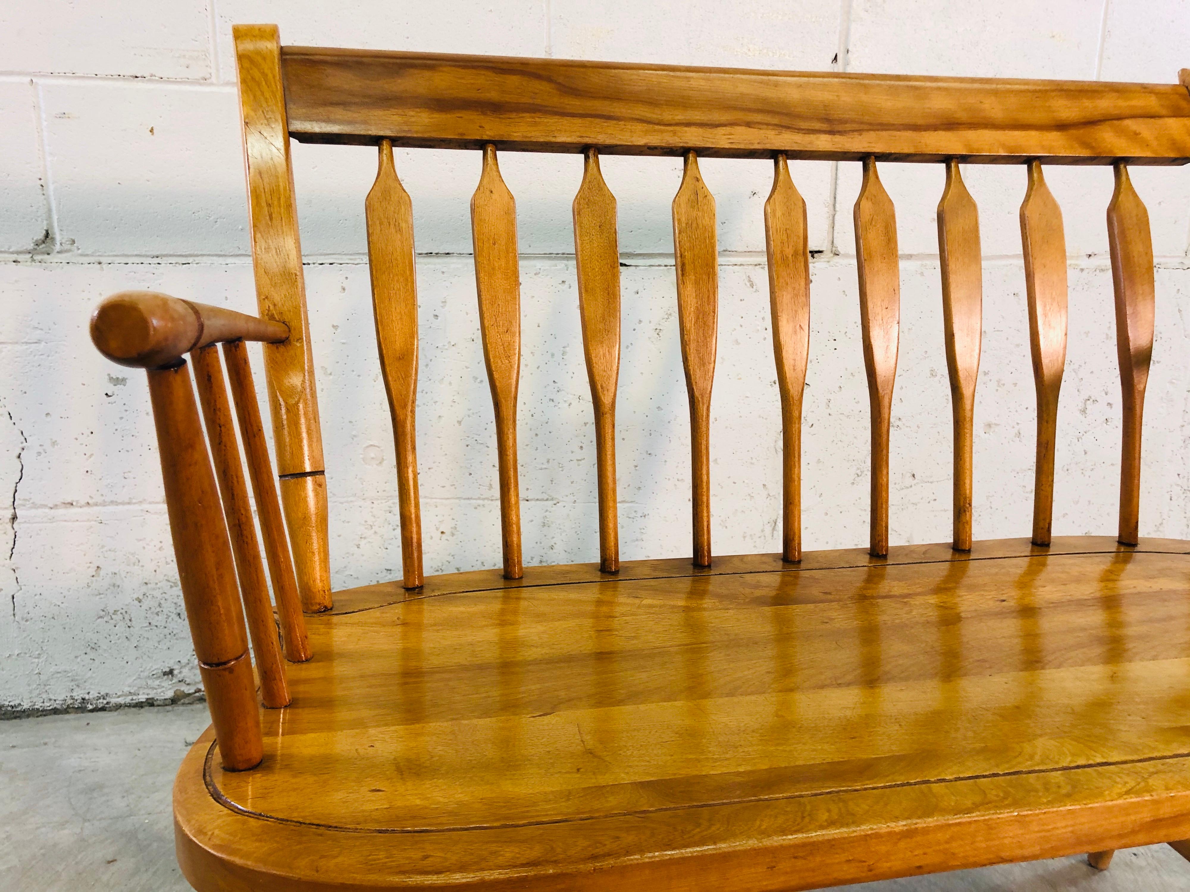 Vintage maple wood two-seat bench designed by Nichols & Stone of Gardner MA. Bench is solid maple wood with arms and a curve spindle back. Marked underneath.