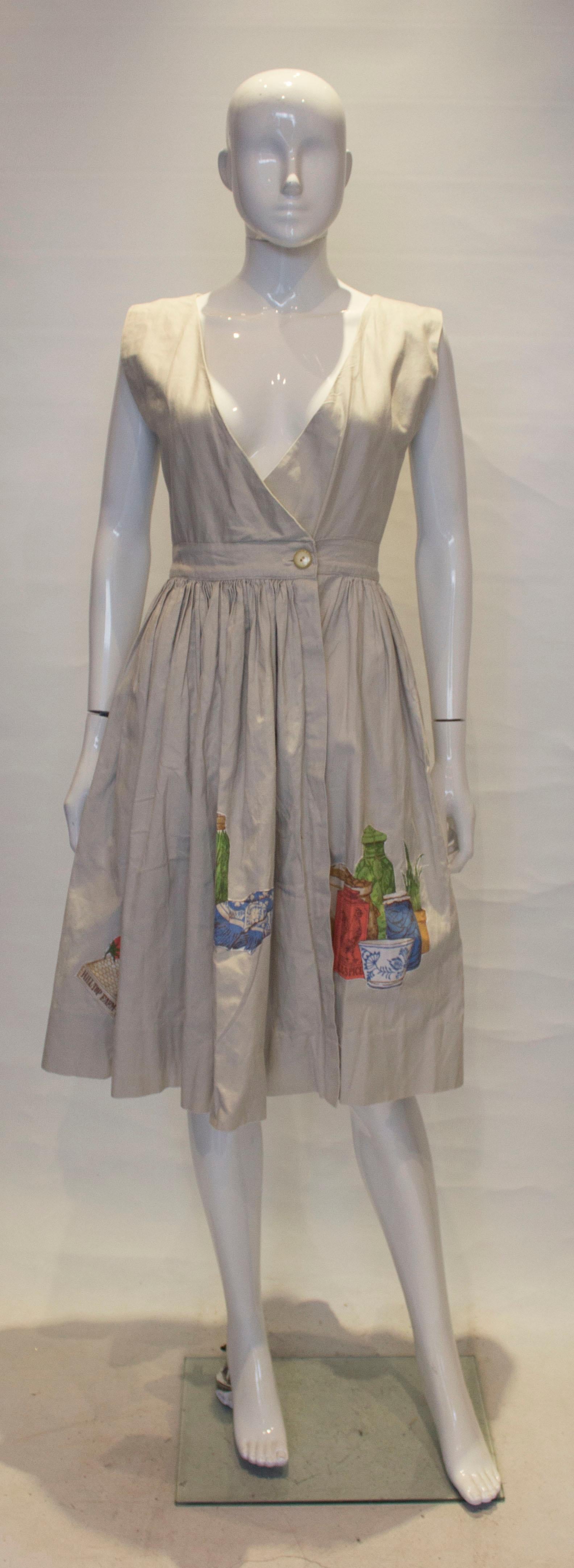 A fun dress from Nieman Marcus. The dress is in a dove grey linen with a wrap over front and pocket on either side. On the lower skirt area area are decorative food detail.