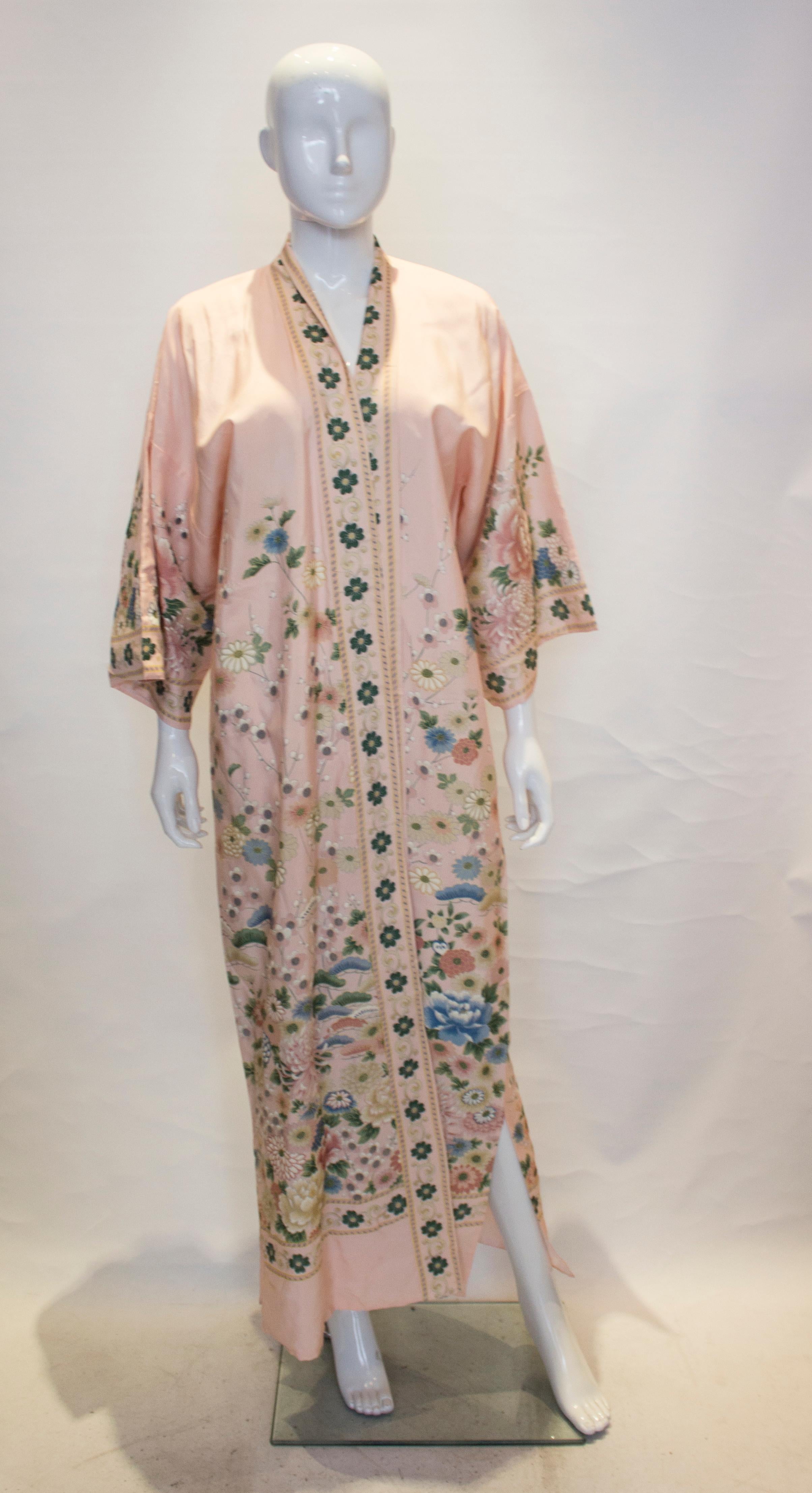 A terribly pretty pink silk vintage kimono, stocked in Nieman Marcus.  The silk kimono has a pale pink background and floral design in blue, pink and green.  It has elbow length sleaves , a 12'' slit on either side and is fully lined. The kimono