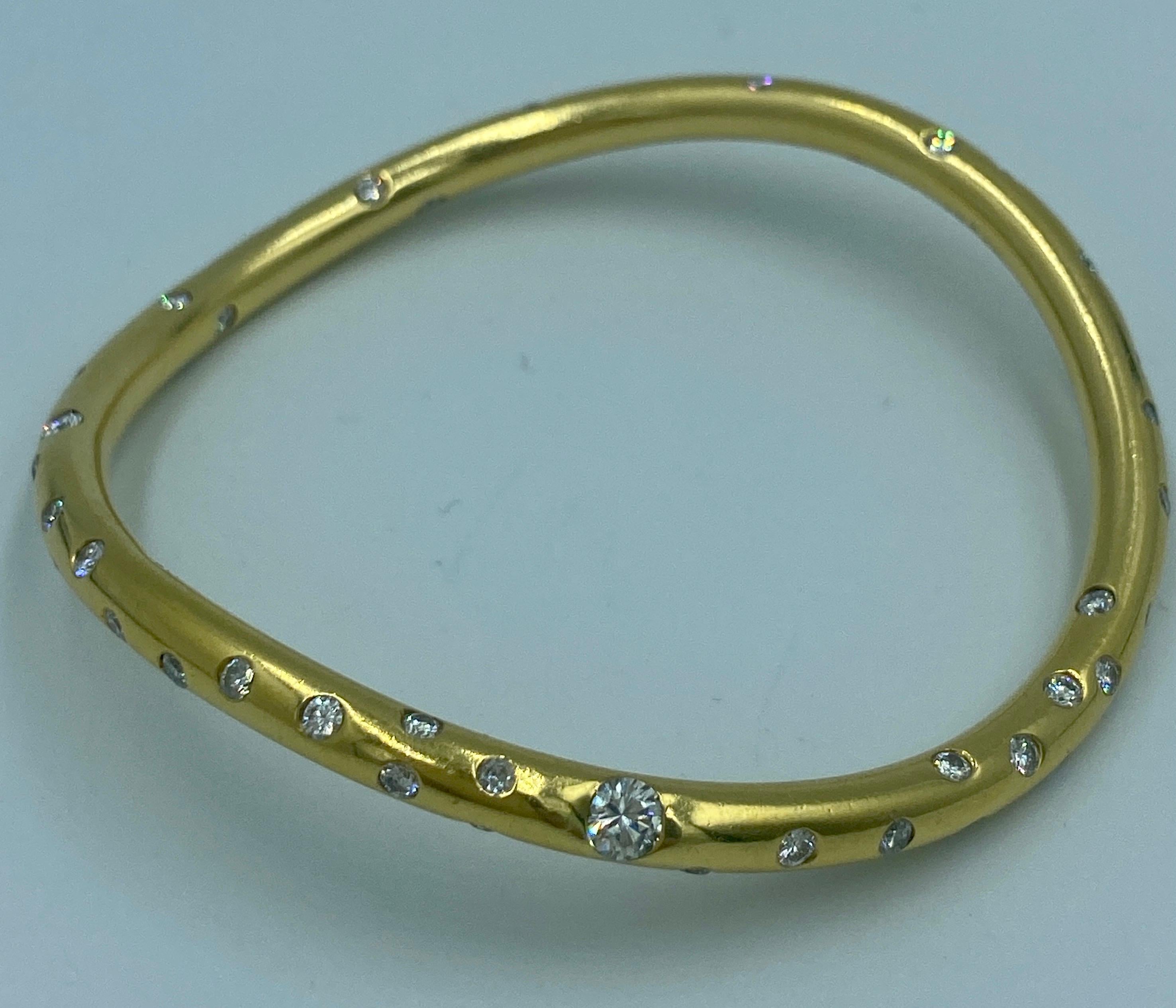 This 18 k gold Niessing bangle is studded with varying sizes of round cut diamonds. It is a hefty piece at 58 g. Its asymmetric design and the many diamonds make this a most attractive stylish piece of jewellery.