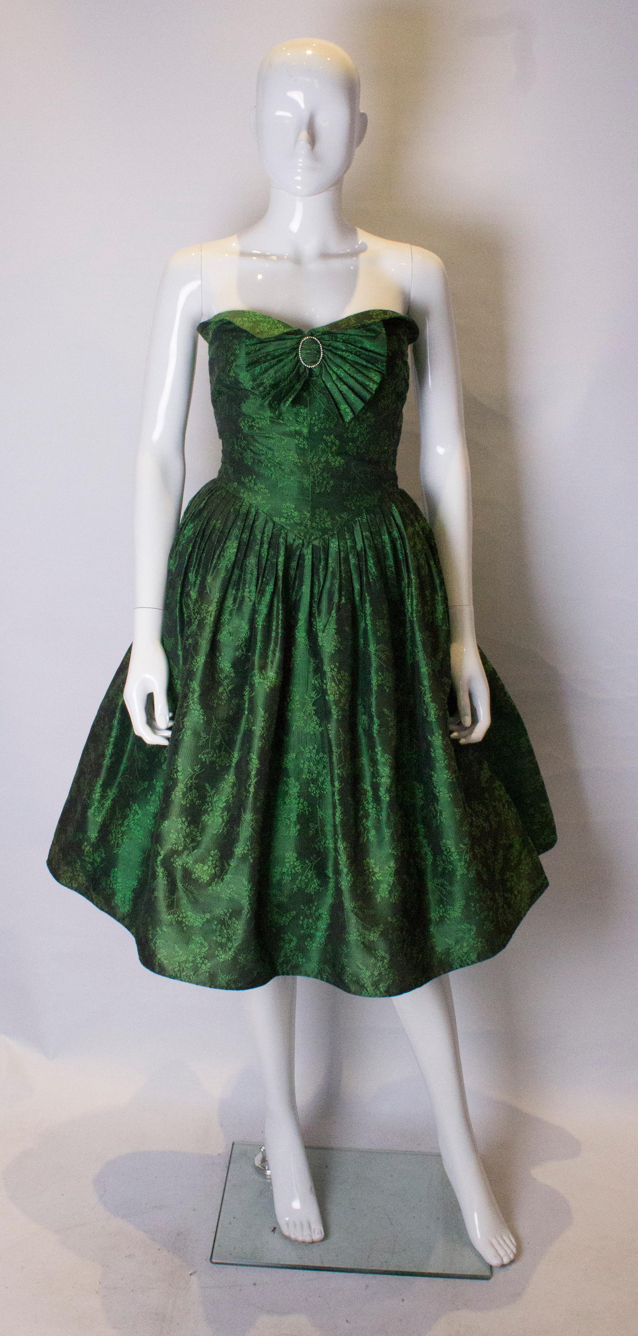 A stunning cocktail dress by Nina Ricci Haute Boutique. In a green silk with a floral design and a wonderful green silk lining, the dress is wonderfully constructed. It is stapless with a turn down front and a central back zip.