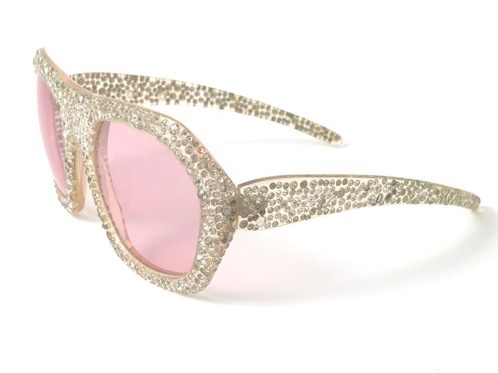 Collectors Item. 

Nina Ricci's oversized bejewelled with different sizes of rhinestones frame sporting a pair of flawless rose lenses.

Made in Paris.
 
Produced and design in 1970's.

Some of the rhinestones have darkened. The frame has light