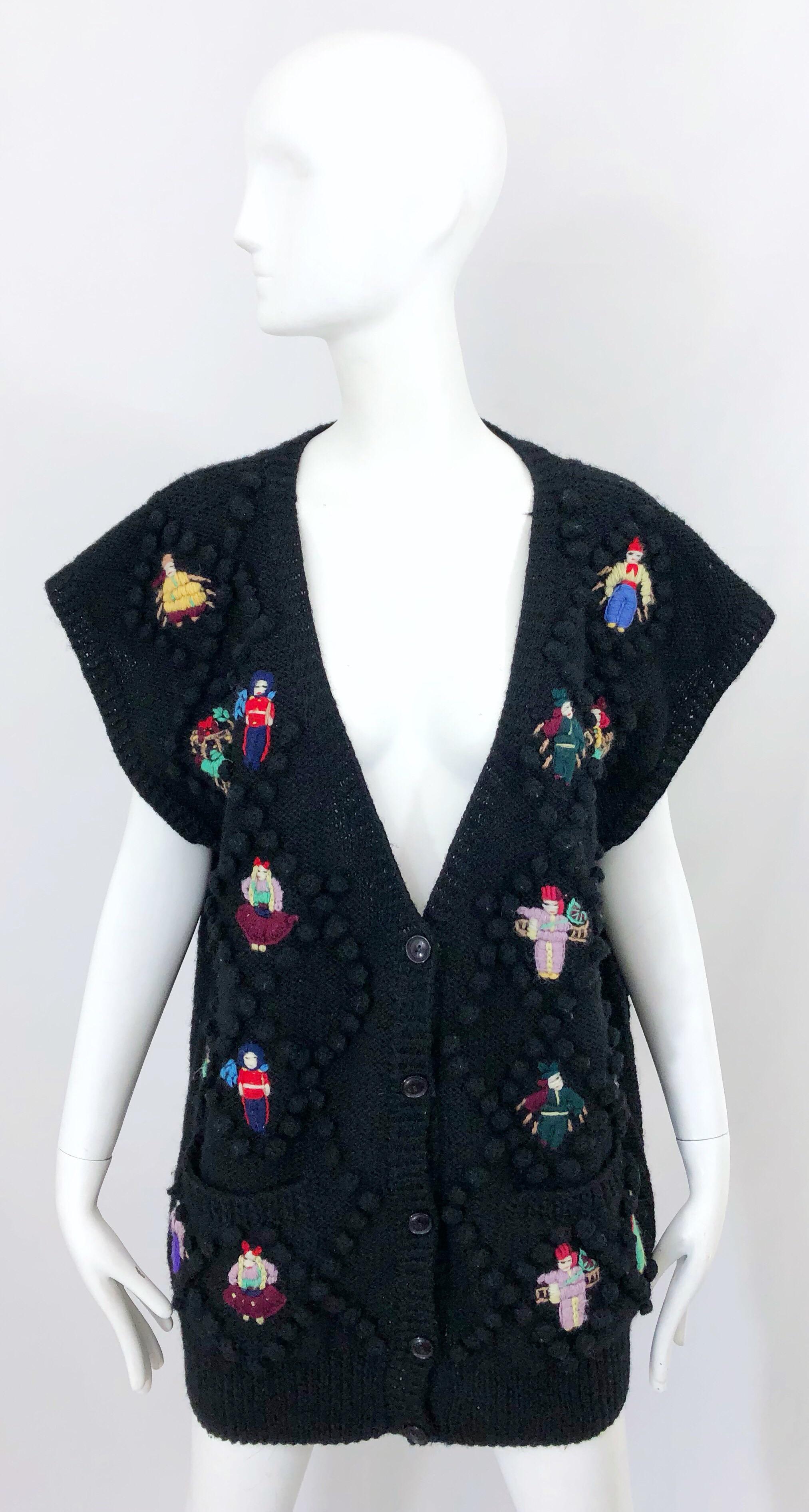 Rare 80s NORMA KAMALI black wool Avant Garde doll appliqués sleeveless slouchy sweater vest! Features ten intricately sewn doll appliqués one each side of the front. Black pom poms symmetrically throughout. Five buttons up the front. Chic dolman