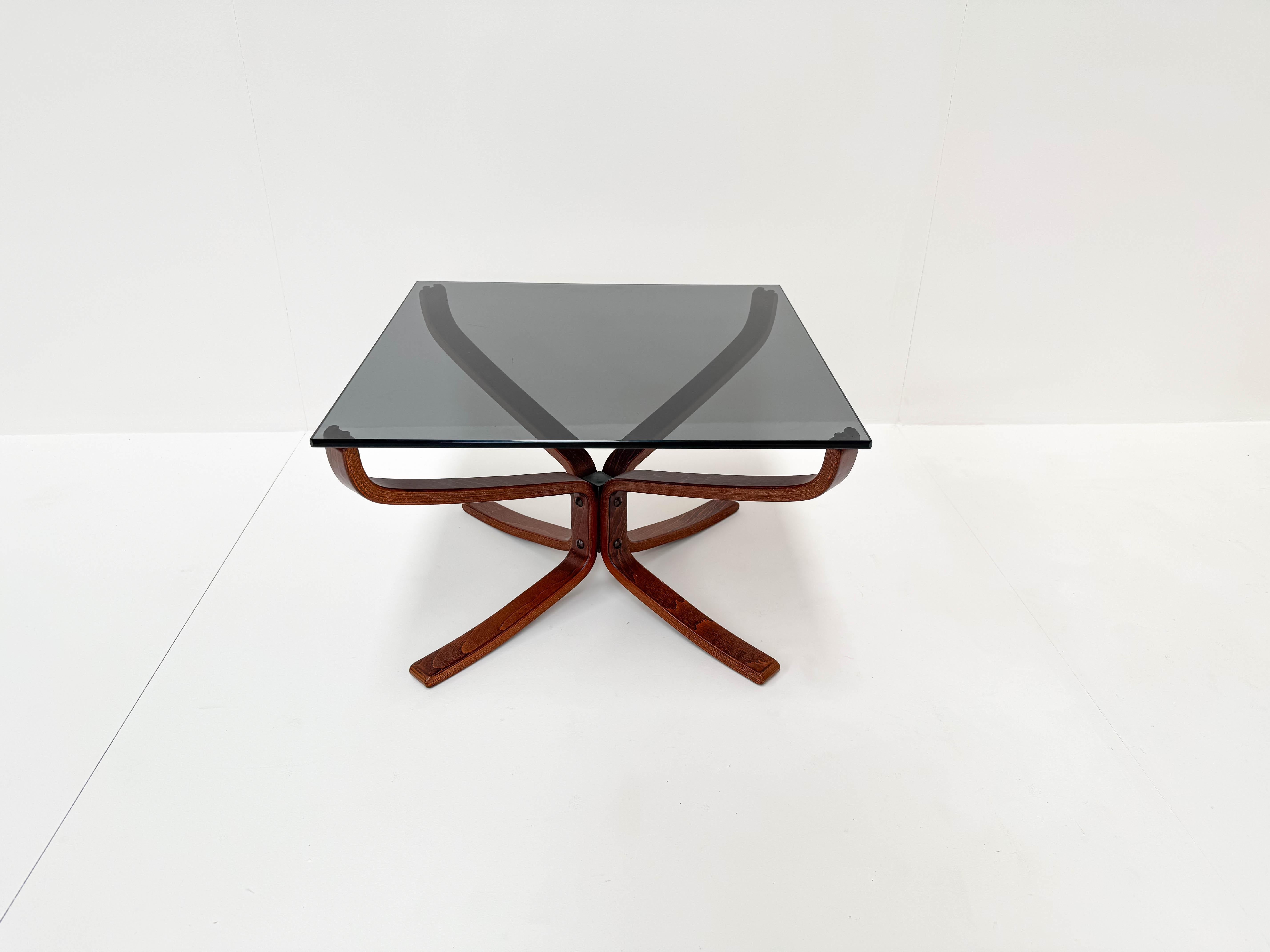This elegant square coffee table was designed by Sigurd Resell for Vatne Møbler in Norway during the 1960s. It features a sculptural bentwood base in dark stained wood and a smoked glass top. The design is both minimal and organic, showcasing the