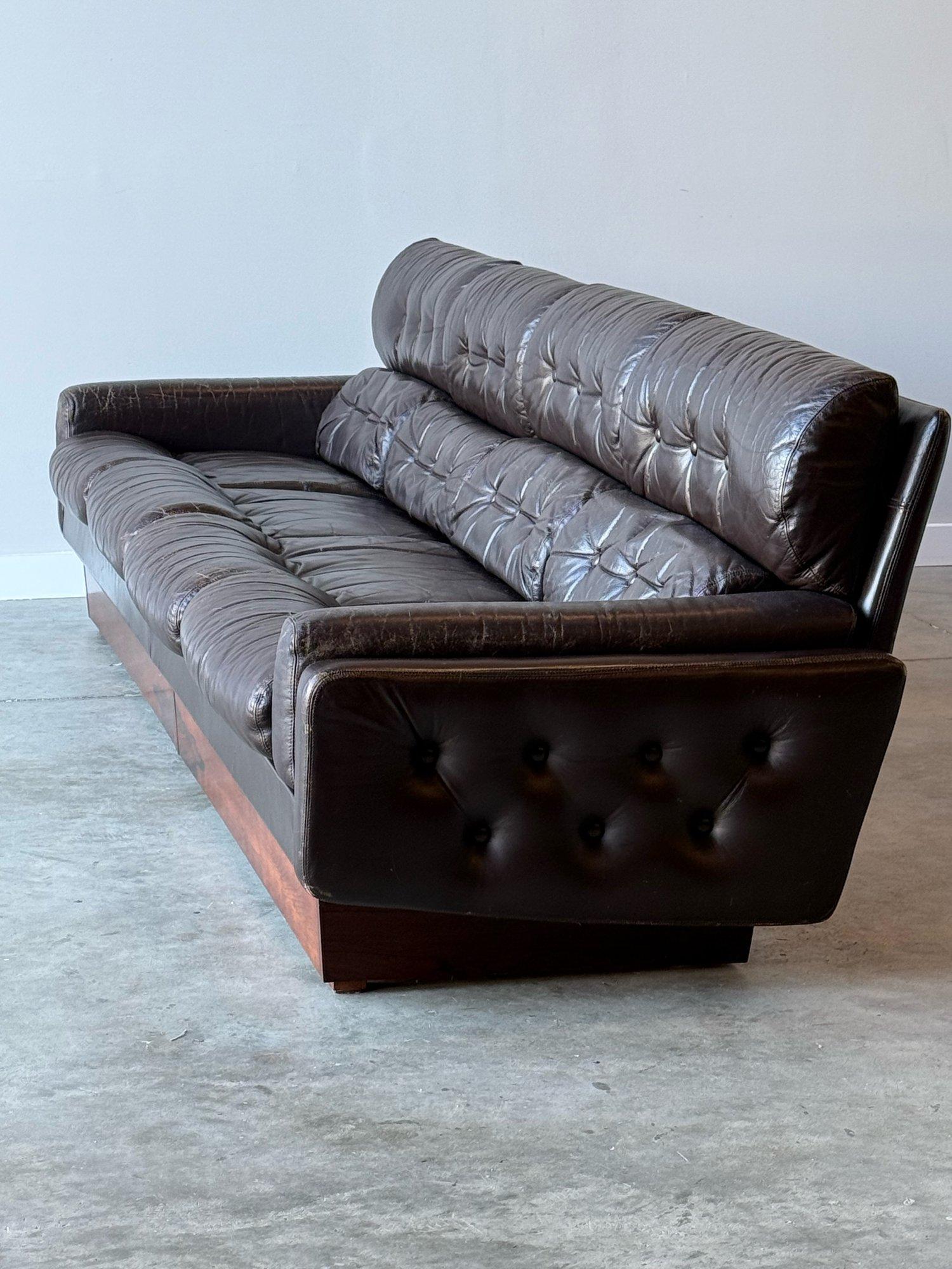 Divano vintage di metà secolo in pelle e palissandro norvegese. Con le sembianze di Ekornes e Arne Norells. Profilo distintivo con schienale alto e base a piattaforma aerodinamica.

Questo divano è caratterizzato da un design classico con inserti e