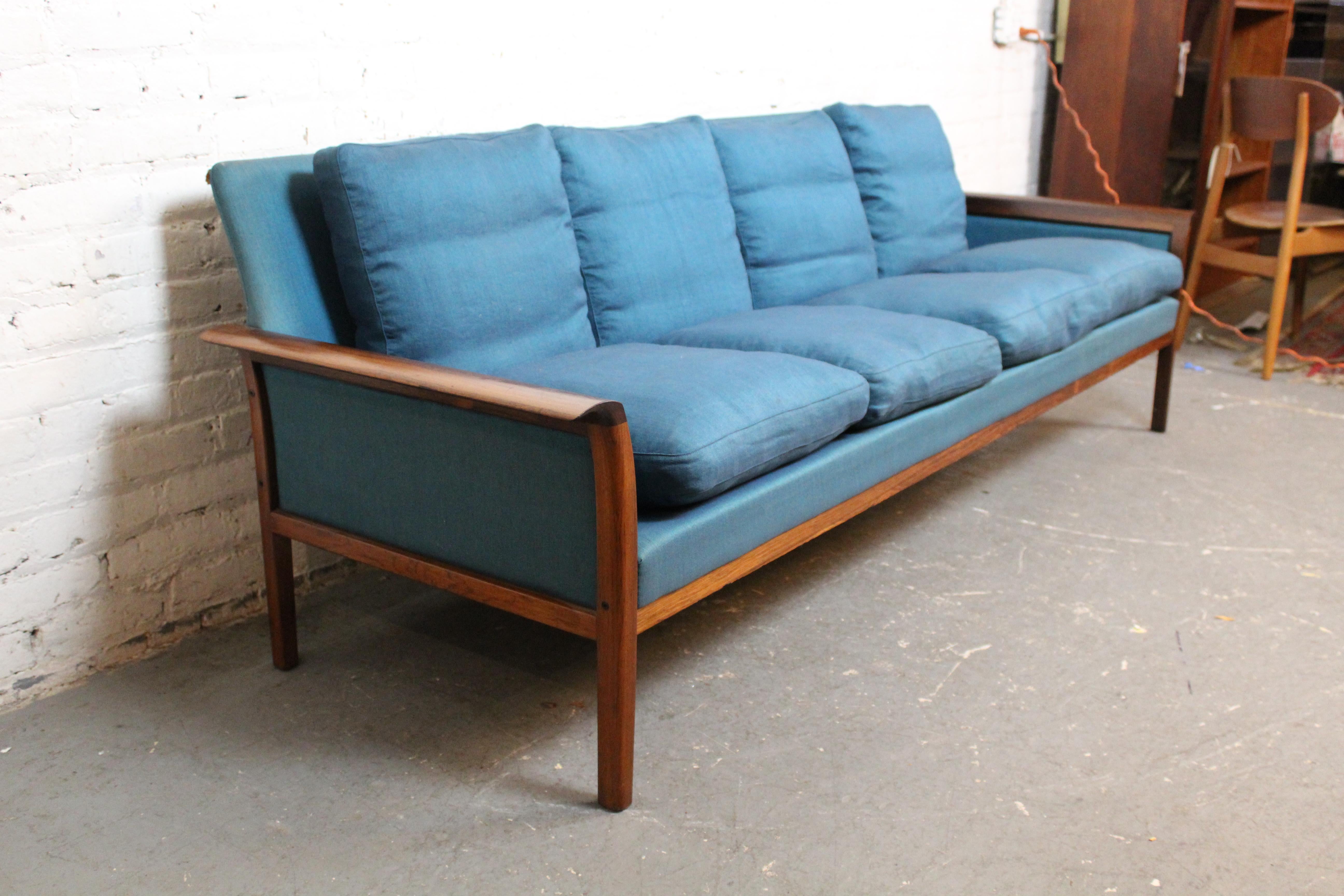 Bring home the refined simple luxury of mid-century Norwegian Modern furniture with this exceptionally exquisite sofa designed by Hans Olsen of Denmark for Norway's Vatne Møbler brand. With a frame carved from solid rosewood, the armrests highlight