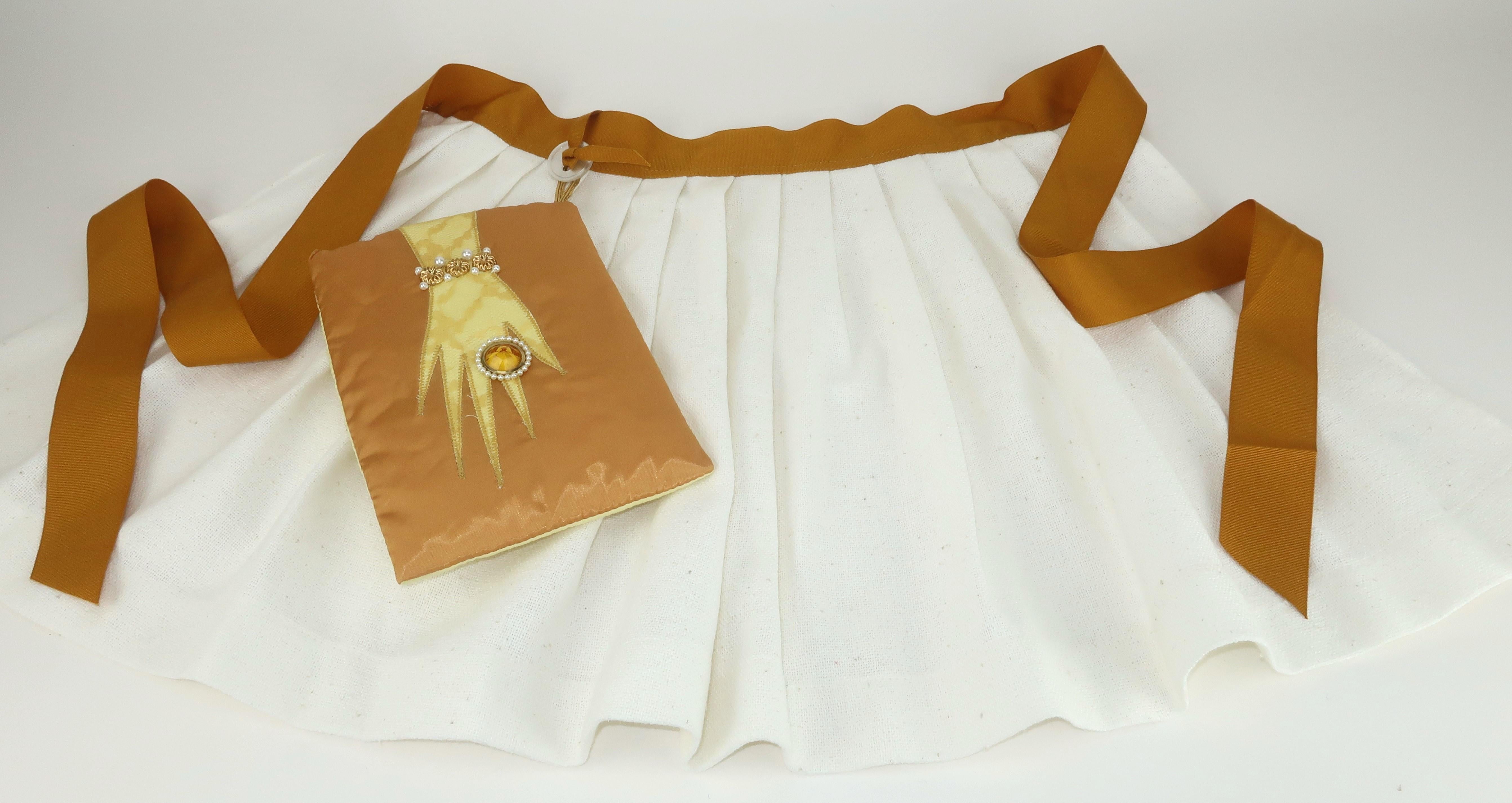 For the hostess with the mostest!  Glam C.1960 pleated apron and attached oven mitt embellished with a stylized hand.  The apron is a bleached burlap trimmed in golden yellow grosgrain ribbon.  The satin oven mitt attaches with a button at the waist