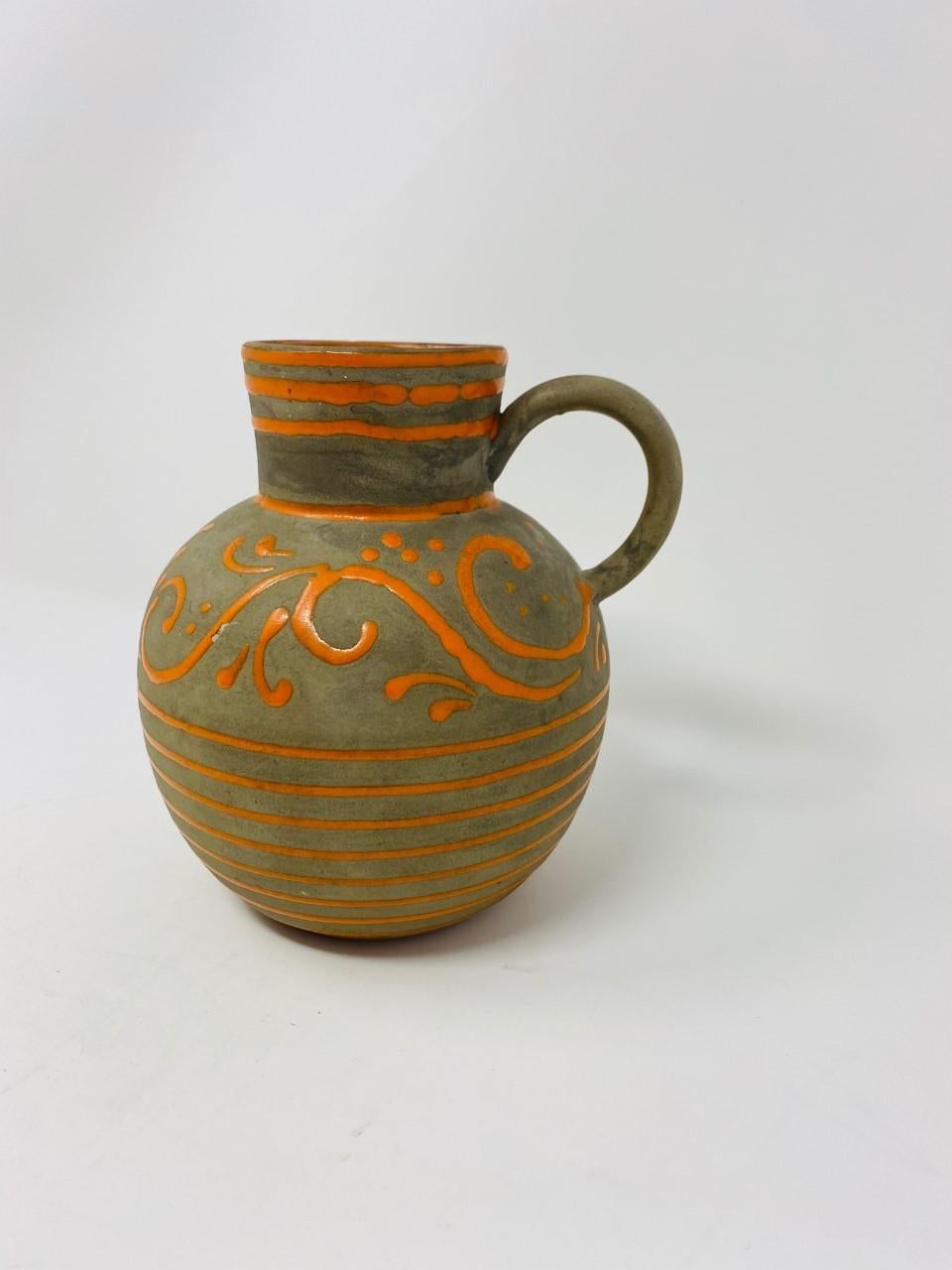 Rare jarre ou vase en poterie de Nittsjö Keramik. Magnifiquement fabriquée, cette pièce vintage apporte style et joie aux yeux. Décoré et émaillé à la main en gris taupe foncé avec des bandes horizontales orange et un motif décoratif de lignes