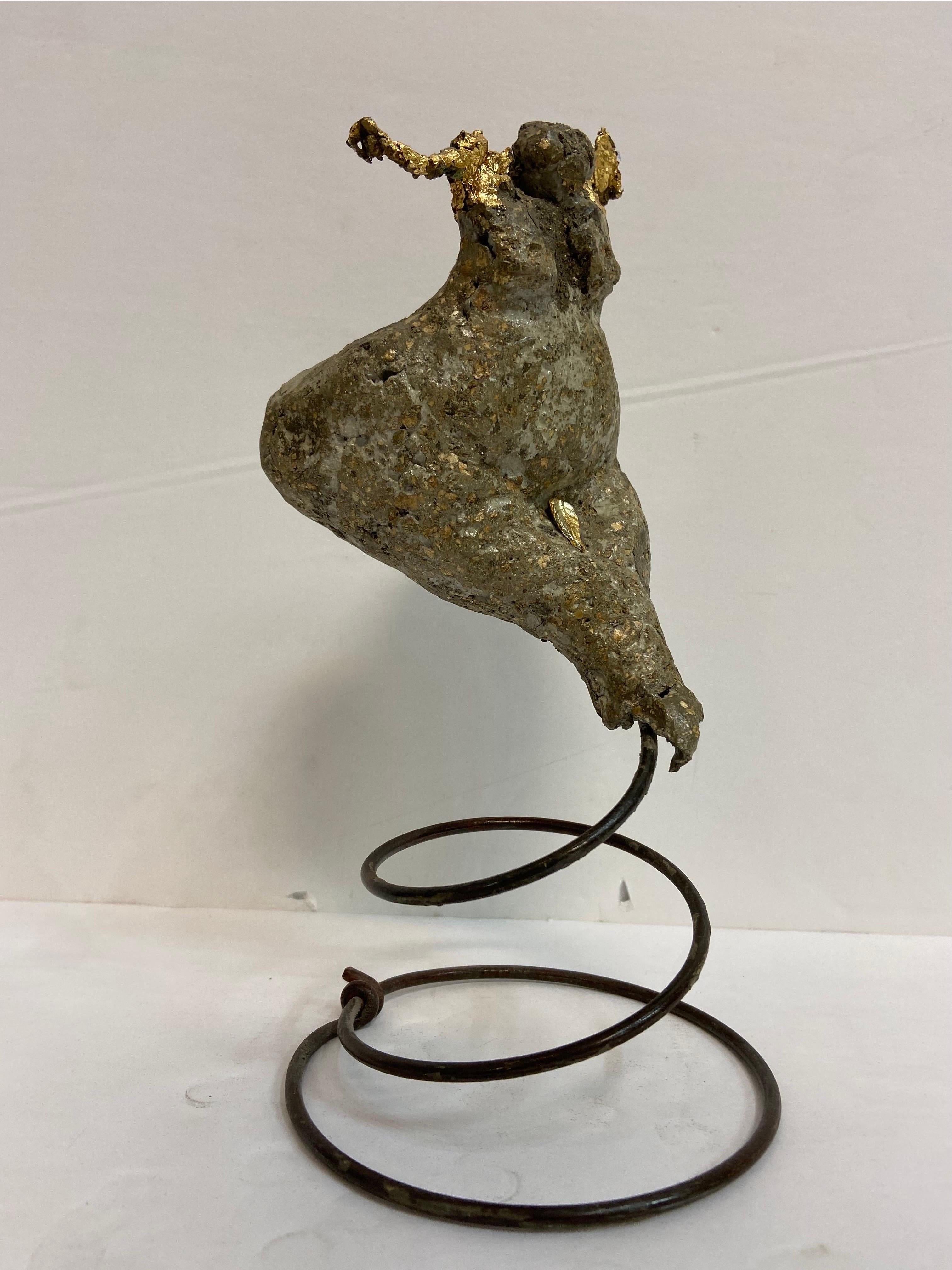 A whimsical and powerful representation of the female form by Contemporary American artist Larry McLaughlin (born 1956). This sculpture is constructed of concrete and heightened with gold leaf. The sculpture is set atop a coiled metal spring. The