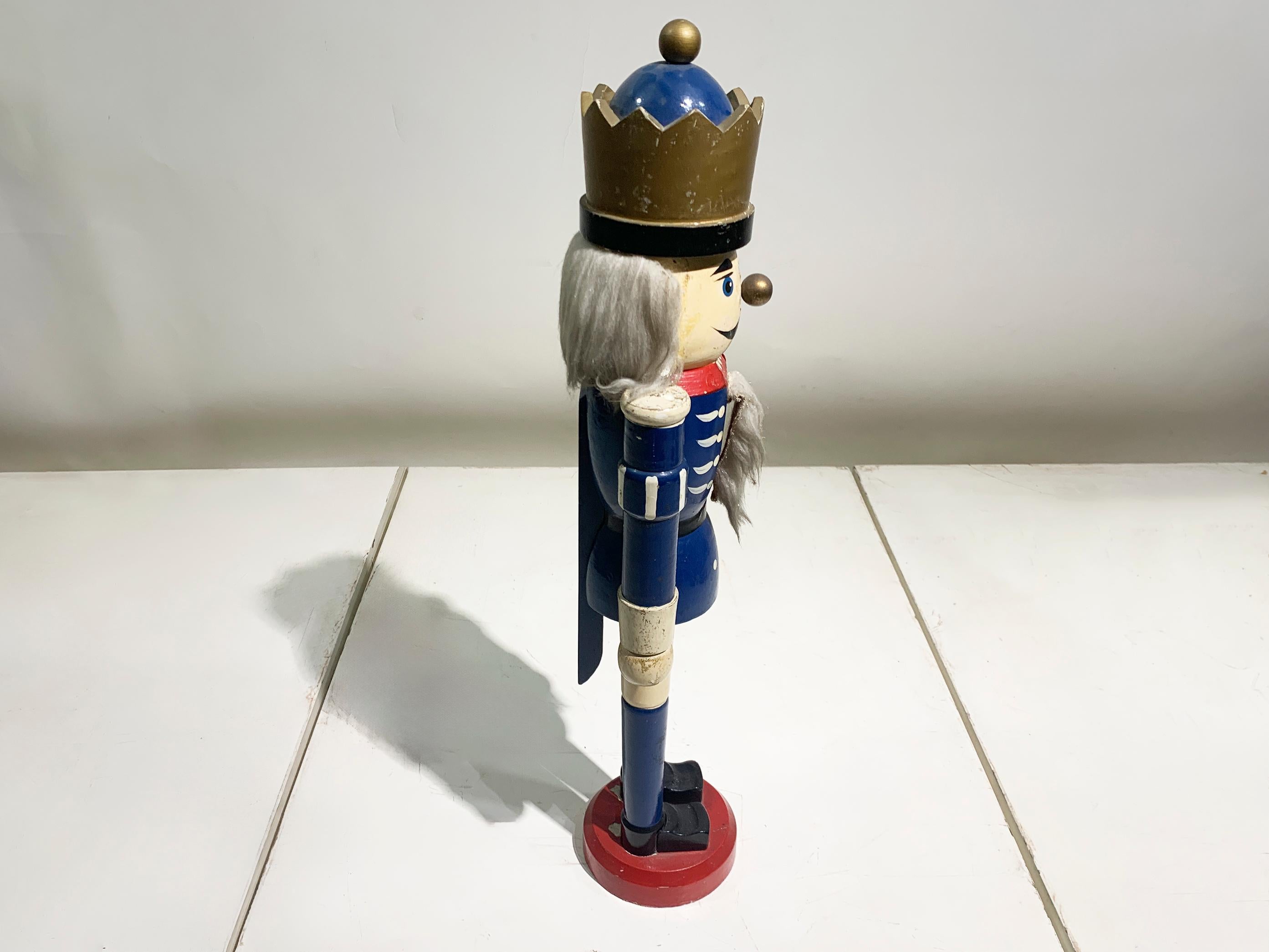 Questo straordinario schiaccianoci vintage è un bellissimo esempio di arte popolare tedesca tradizionale proveniente dalla regione di Erzgebirge. Realizzato a mano in legno tornito, questo pezzo grande e sostanzioso risale agli anni '70 e mette in