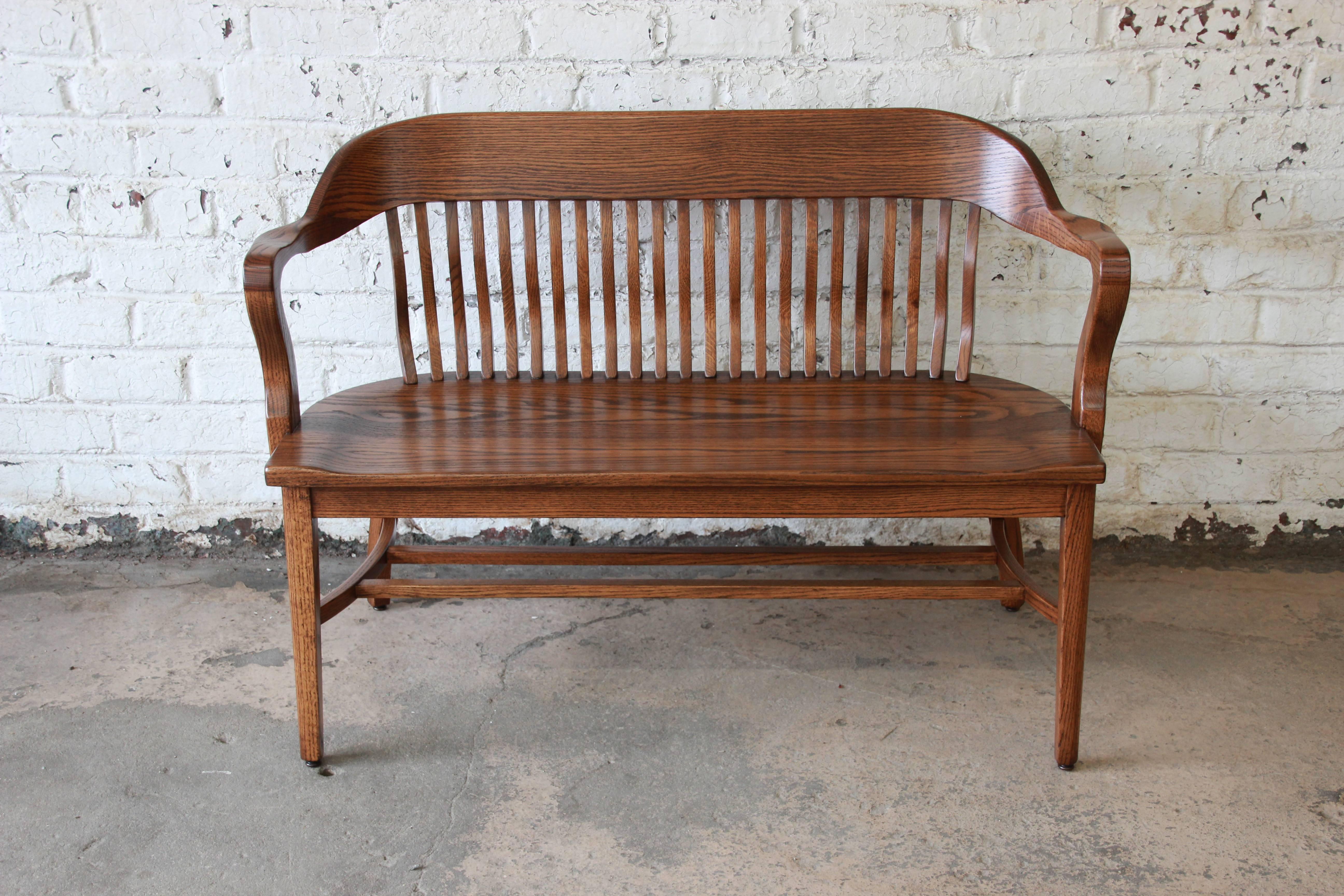 Offering a very nice newly refinished bankers bench in solid oak. The bench has beautiful wood grain and is constructed with quality craftsmanship and detail. The curved back with spindles and armrest provide great comfort on the versatile piece.