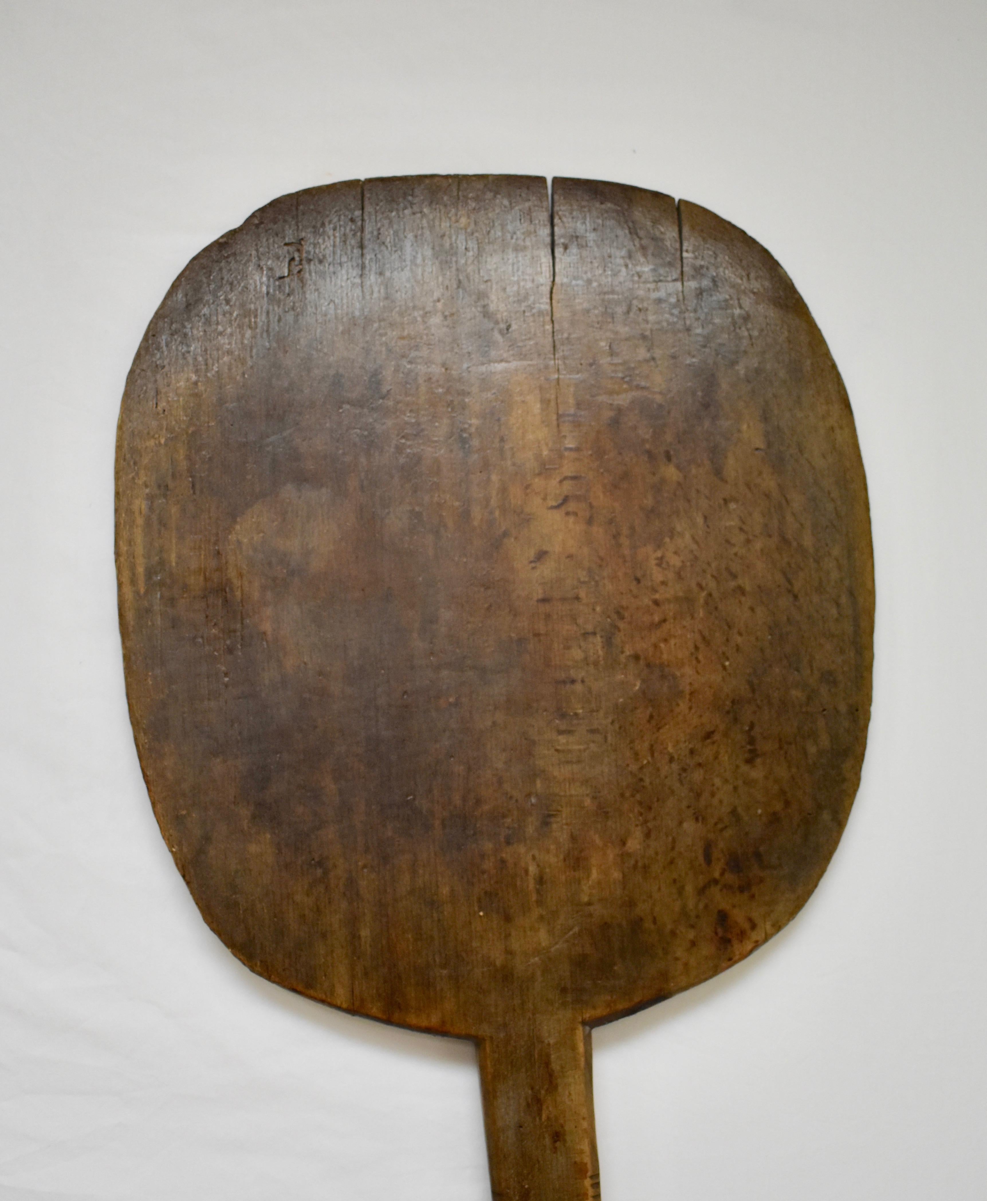 This large vintage oak bread peel has been hand-carved from a single board. The shaft is worn smooth and the paddle shows slight charring and two or three minor cracks to the lip.