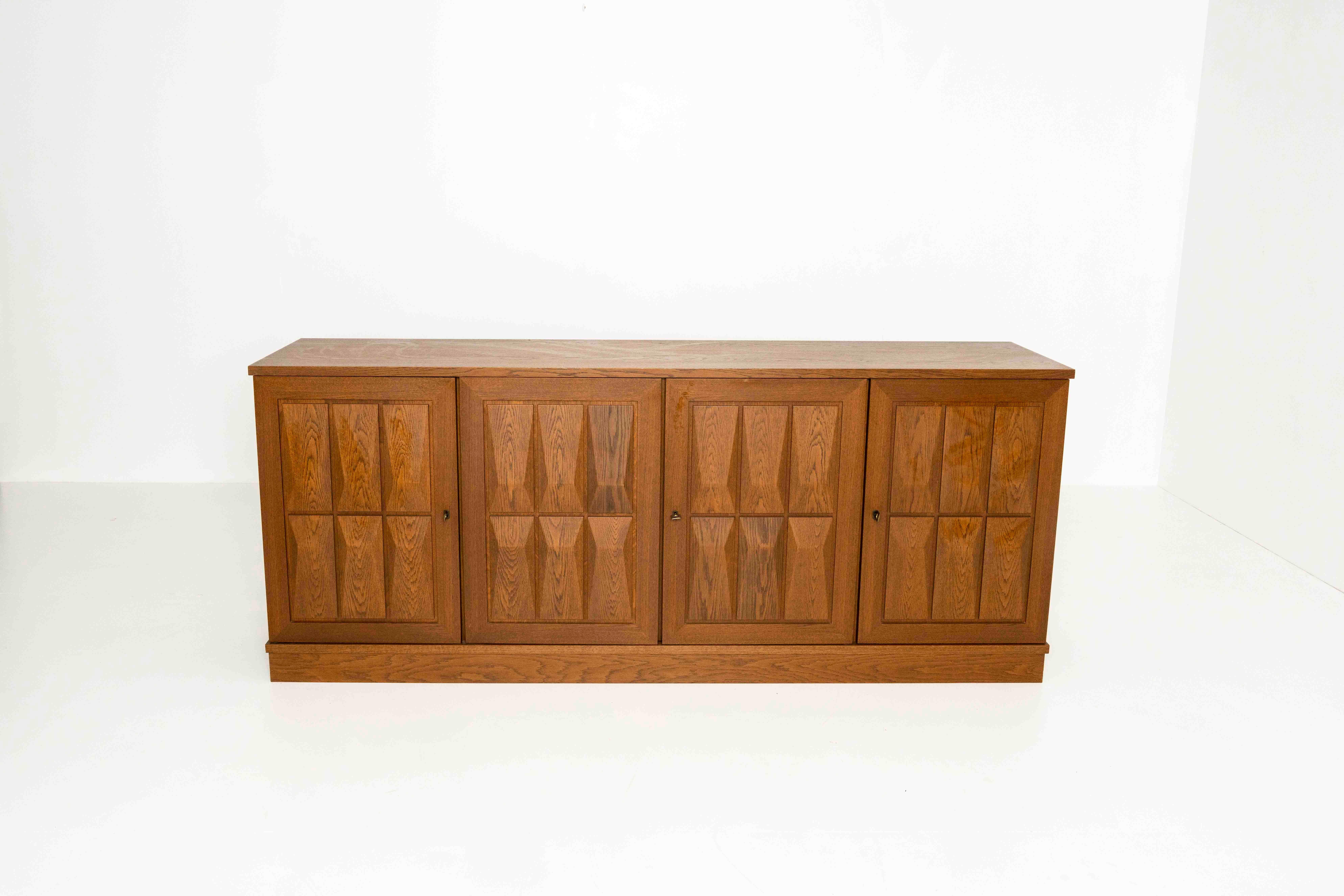 Vintage Oak Brutalist sideboard in the Style of Gerhard Bartels from Germany, ca the 1970s. This sideboard has four panels with 'diamond-shaped' rectangles, hiding several shelves and a drawer. Some shelves are from a later period. There are three