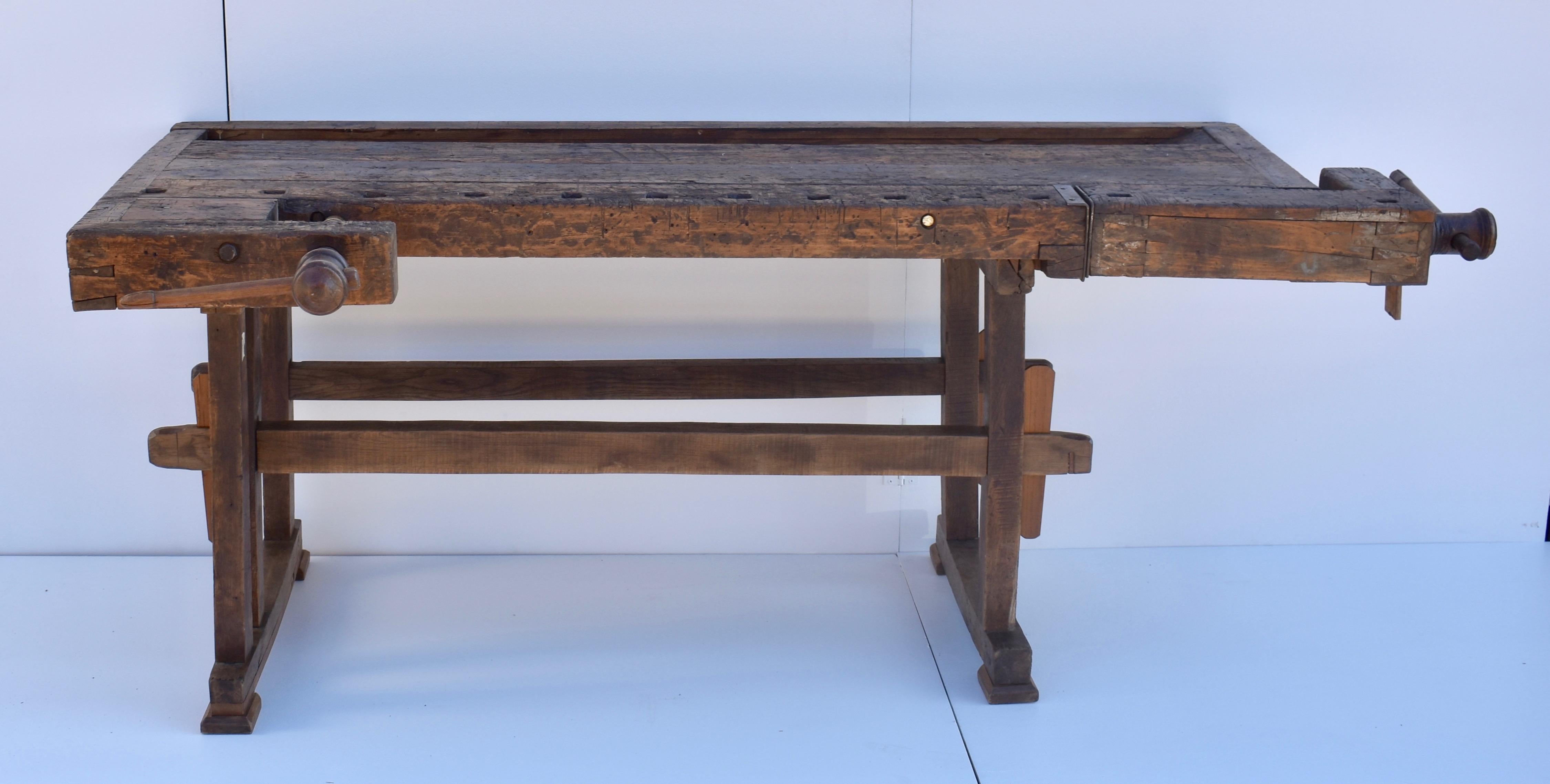 This is an outstanding vintage carpenter’s workbench, built as solid as a rock. The trestle-style base is made entirely of oak. The uprights are hand-cut, through-tenoned and pegged top and bottom to the horizontal members. The trestles are joined