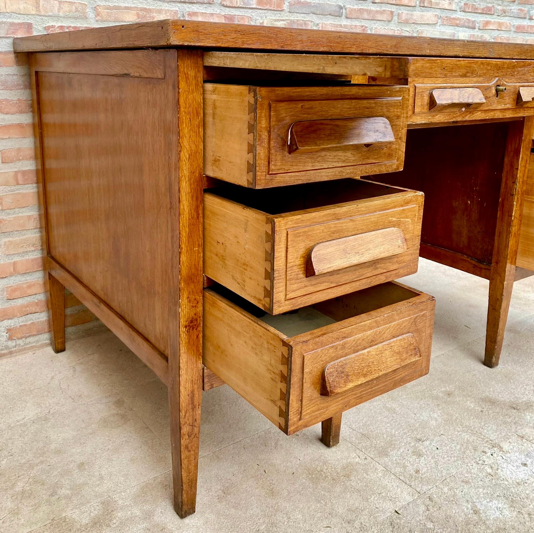 Stunning vintage oak desk, designed in France, circa 1940s. Crafted with meticulous attention to detail, this desk features thoughtful design and wooden handles. Designed with functionality in mind, it has six dovetail drawers along the sides, a
