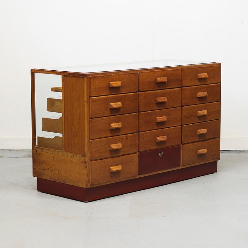 Ein Zähler aus den 1950er Jahren, hergestellt von Soeschala in Stuttgart-Zuffenhausen. Die Theke hat nicht weniger als 15 Schubladen, die stufenförmig nach unten verlaufen. Die Schubladenfronten sind aus Glas und ermöglichen eine klare Sicht auf den