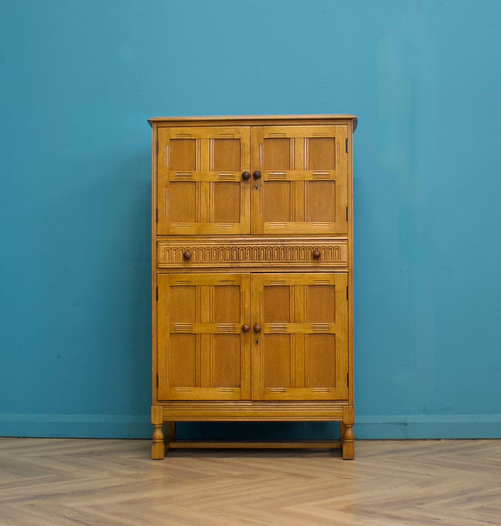 A beautiful oak drinks cabinet, circa 1960s.


Featuring two lockable cupboards and a drawer to the middle.


Inside the drinks cabinet cupboard is a mirrored back with a glass shelf, a pull out drinks tray and additional shelves to each door.


The