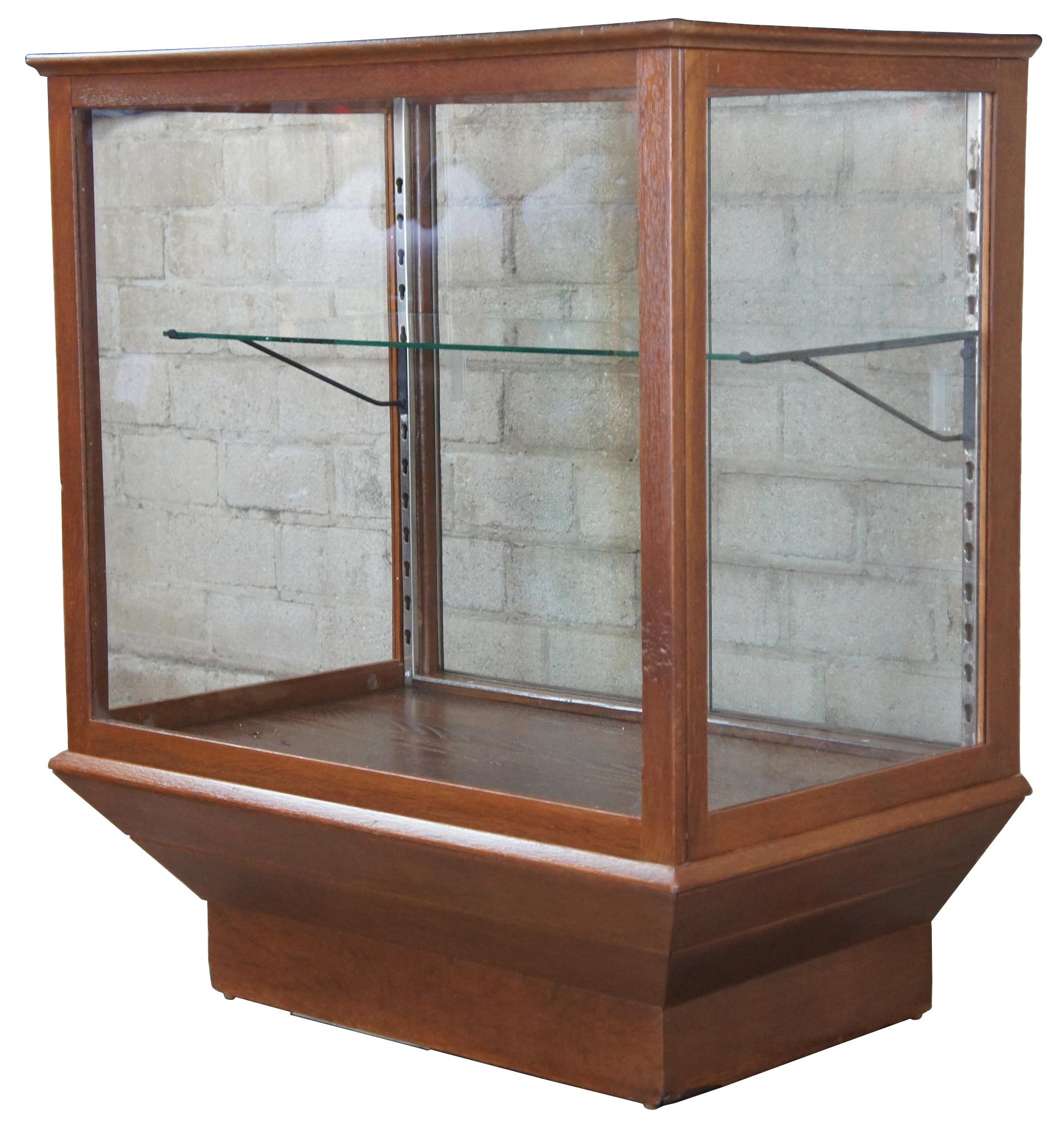 Vintage oak general store curio display showcase. Features pedestal base with one adjustable shelf and two sliding glass doors.
  