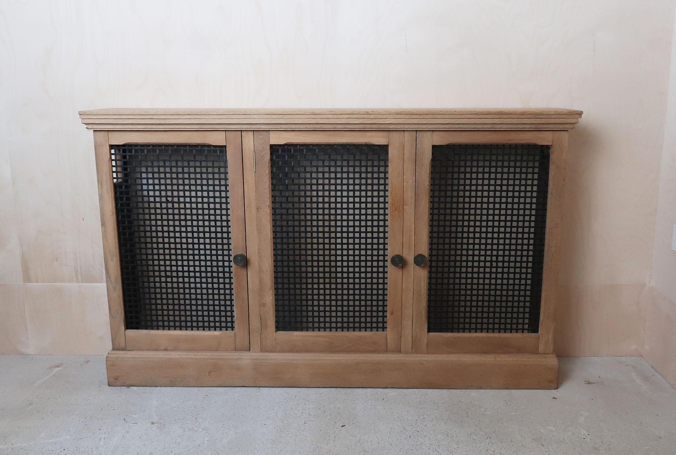 Very smart bare or natural oak cabinet. Originally a radiator cover.

Georgian style.

Original ebonized steel grill panels.

Gaps in the sides of the piece originally for access to the valves. Also cuts at the base where it has followed the shape