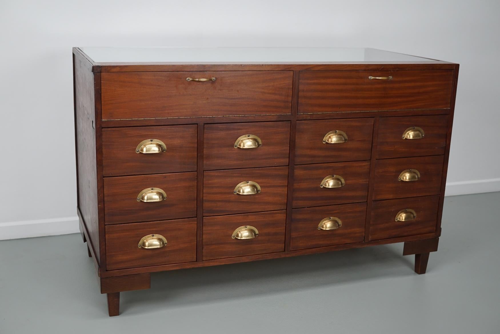 This vintage haberdashery shop counter dates from the 1950/60s and was made in Switzerland. It features a wooden frame, glass casing and drawers in solid mahogany and veneer with brass handles.