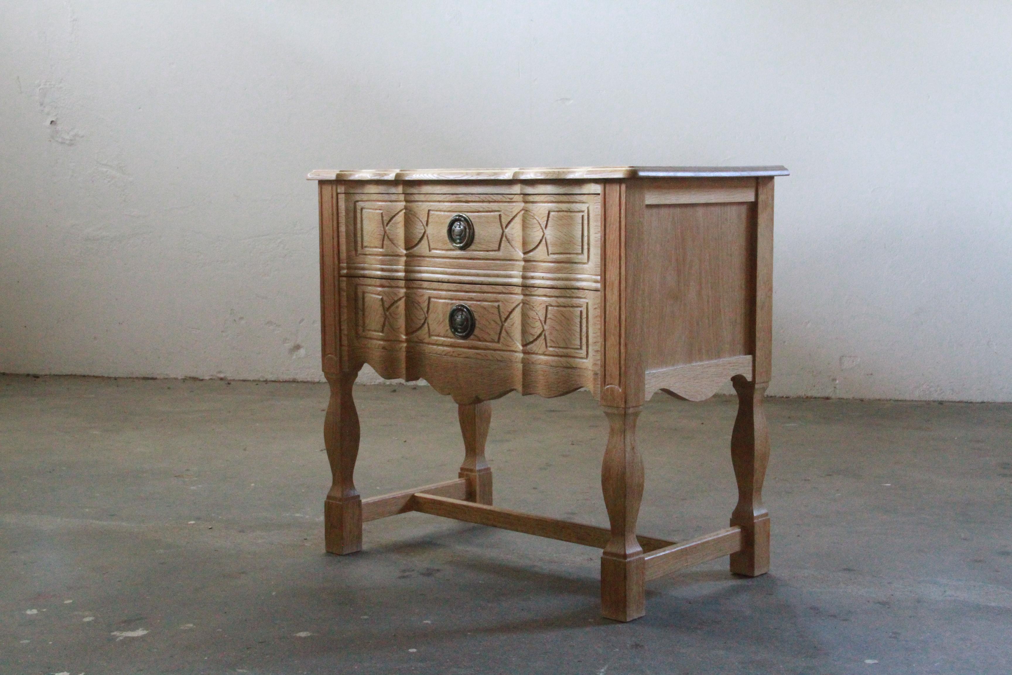 Oak bedside table in the style of Henning Kjærnulf, crafted in the 1960s/70s Denmark. In good vintage condition, this small cabinet, exhibit a poetic blend of baroque and modern design. This rare little piece seamlessly complements diverse interiors