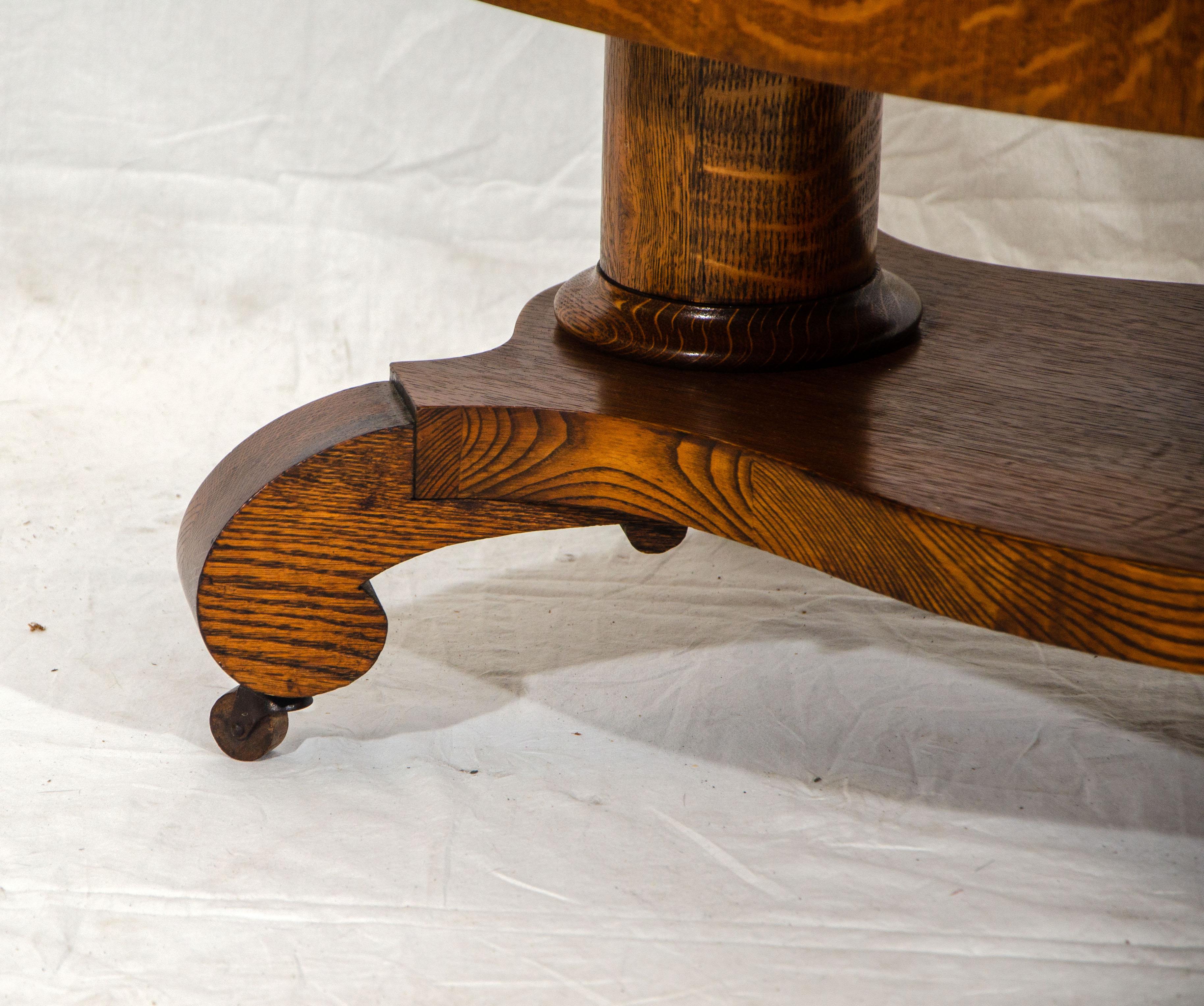 Nice quarter-sawn oak coffee table with a drawer for extra storage space. The two round pedestals connect to a lower shelf accented with curled feet. The table was most likely a taller library table with shortened pedestals. The interior