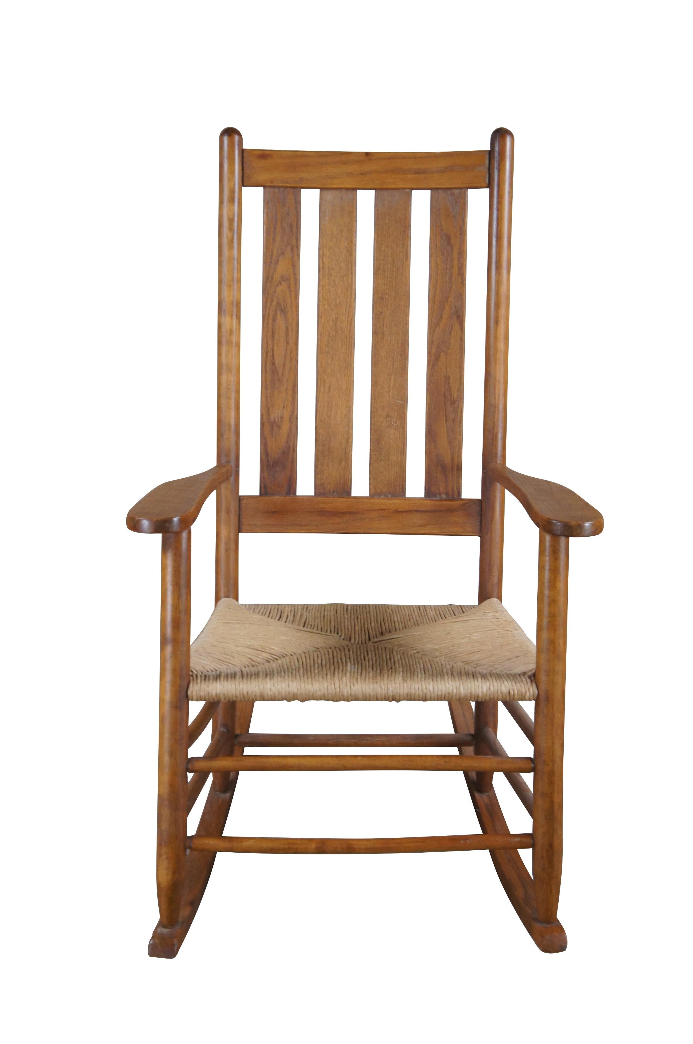 Solid oak American Country / Farmhouse rocking chair.  Features a slat back and woven rush seat.  Includes optional cushions for added comfort. 

Dimensions:
24.5