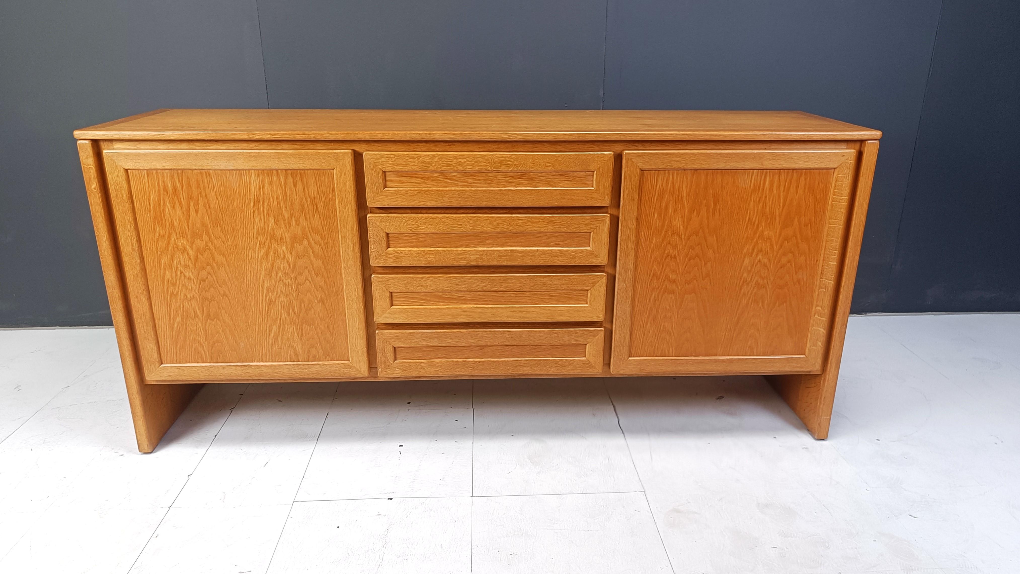 Buffet en chêne de très bonne facture fabriqué en Belgique dans les années 1960

Le buffet est doté de deux portes et de quatre tiroirs centraux offrant un grand espace de rangement.

Un design magnifique et intemporel et une finition de haute
