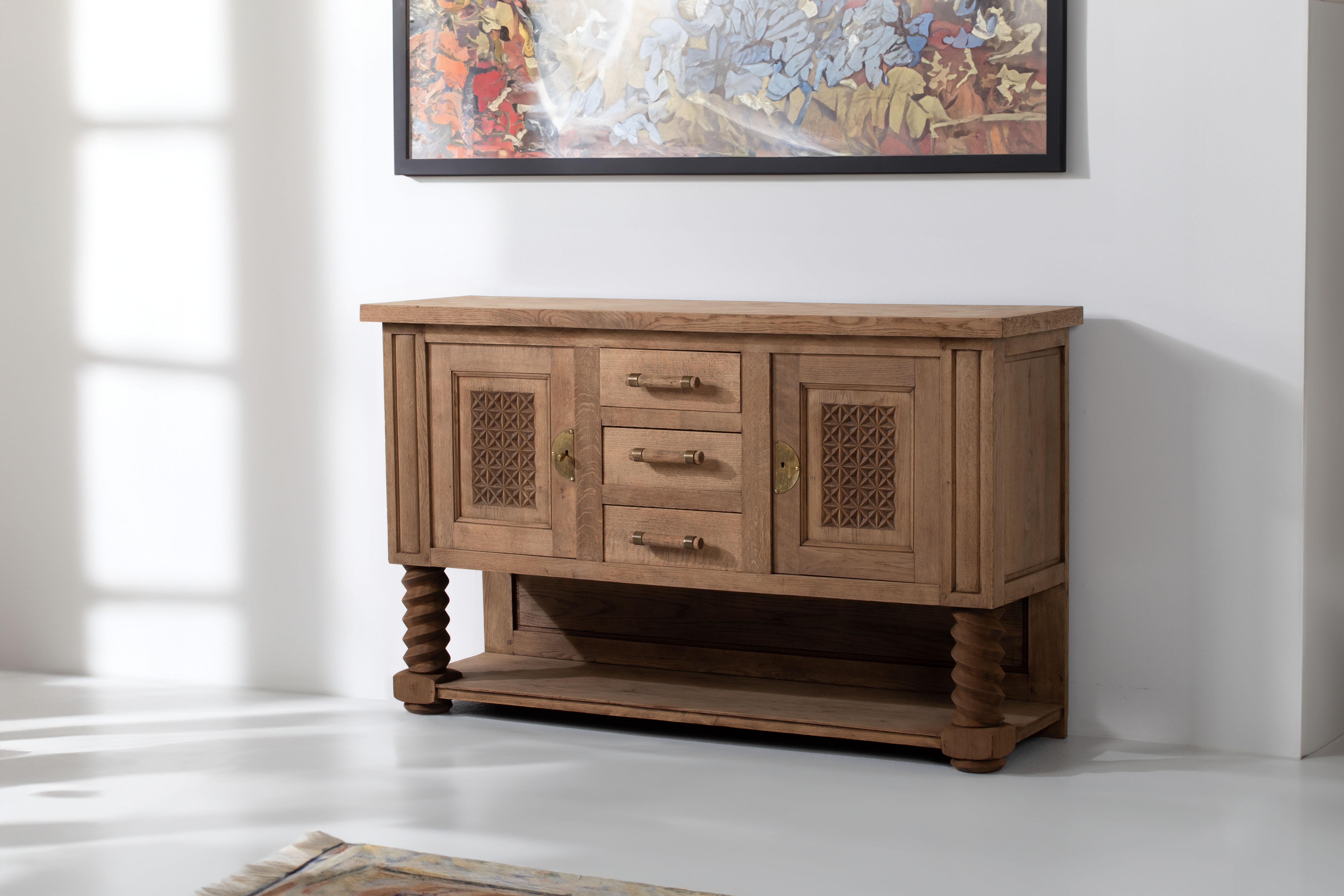 Introducing a Dudouyt-inspired French Oak Sideboard, a timeless piece exuding vintage charm. This exceptional sideboard stands on screw legs, with a low shelf enhancing its storage capabilities. Two spacious compartments offer ample storage, making