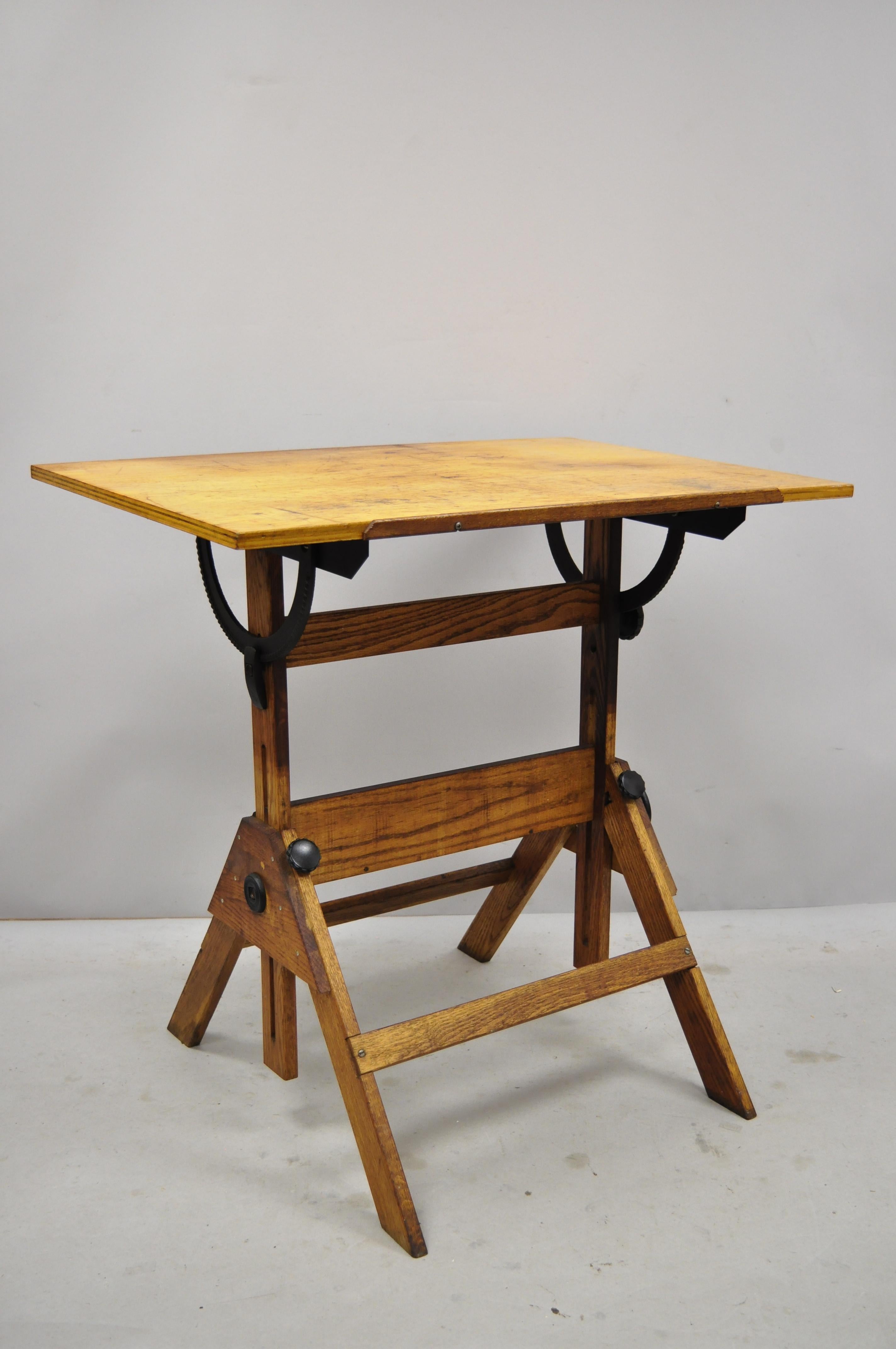 Vintage oakwood and cast iron adjustable small drafting table attributed to Hamilton. Listing includes cast iron hardware, adjustable form, solid wood construction, beautiful wood grain, very nice vintage item, quality American craftsmanship.