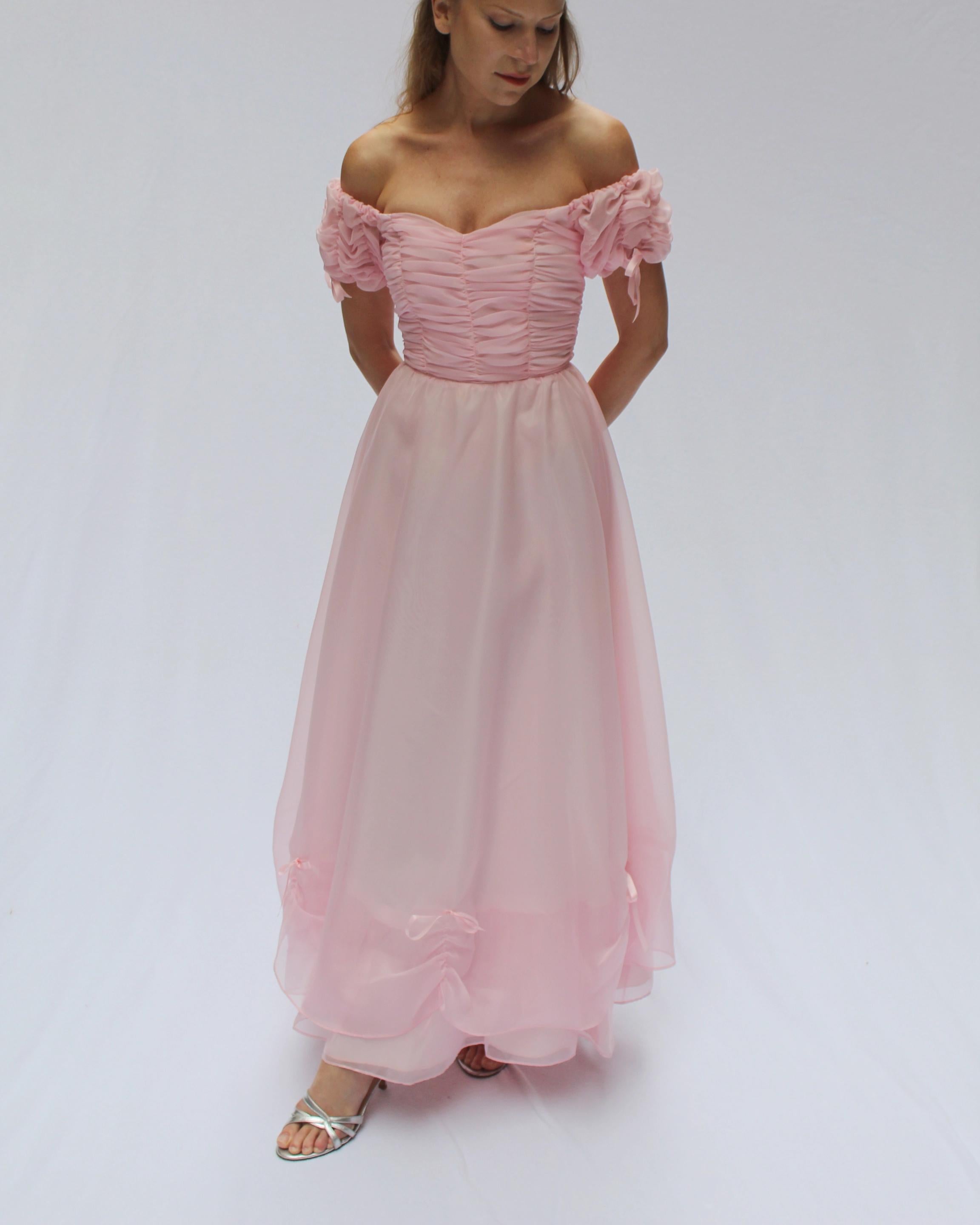 This dreamy vintage off-the-shoulder ballgown is a princess moment brought to life, in the sweetest shade of cotton candy pink. The stunning corseted bodice (with boned interior) is gathered in tiers for the most romantic look. The full skirt