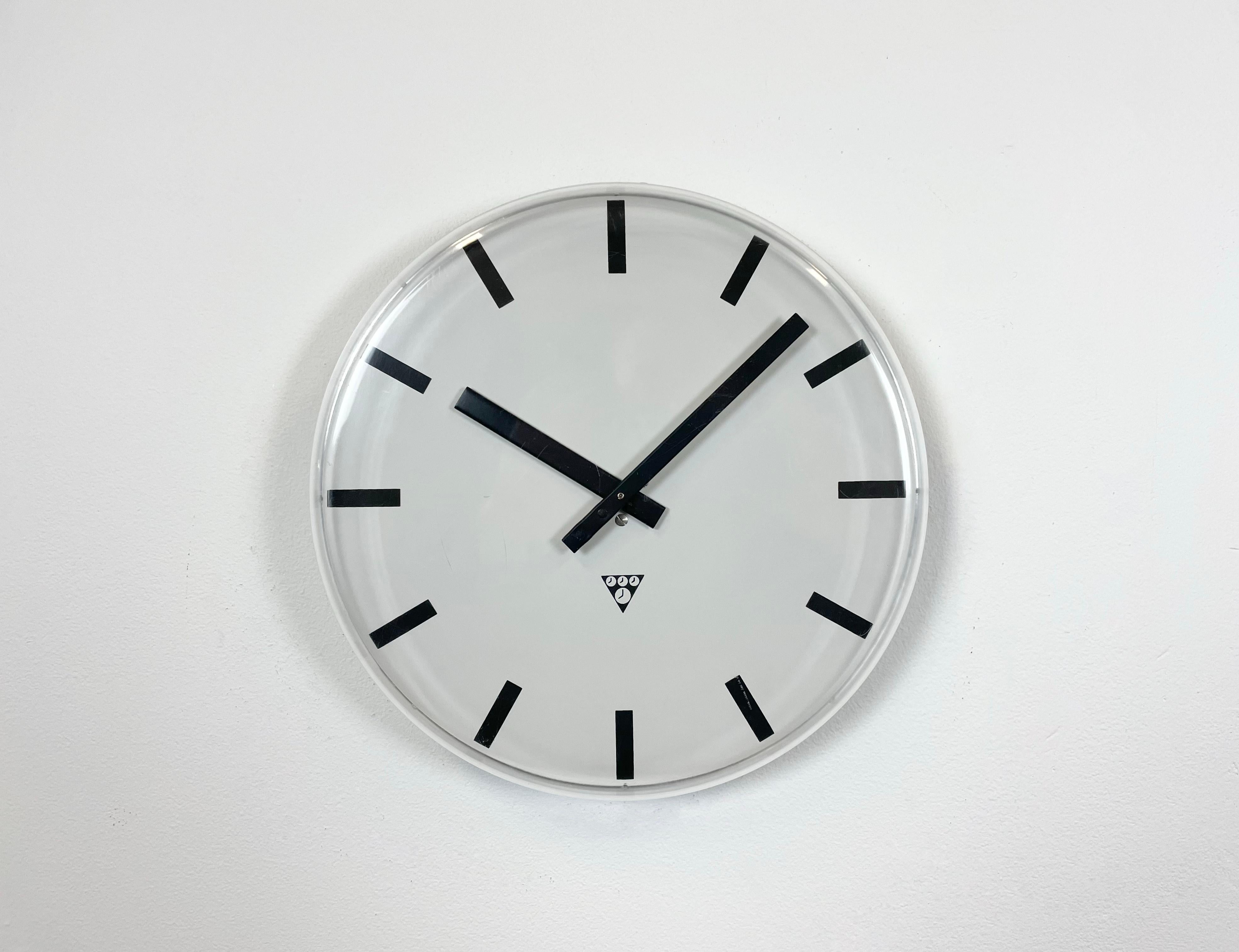 Industrial wall clock was produced by Pragotron in former Czechoslovakia during the 1980s. It features a grey aluminium dial and a curved plastic clear glass cover. The piece has been converted into a battery-powered clockwork and requires only one