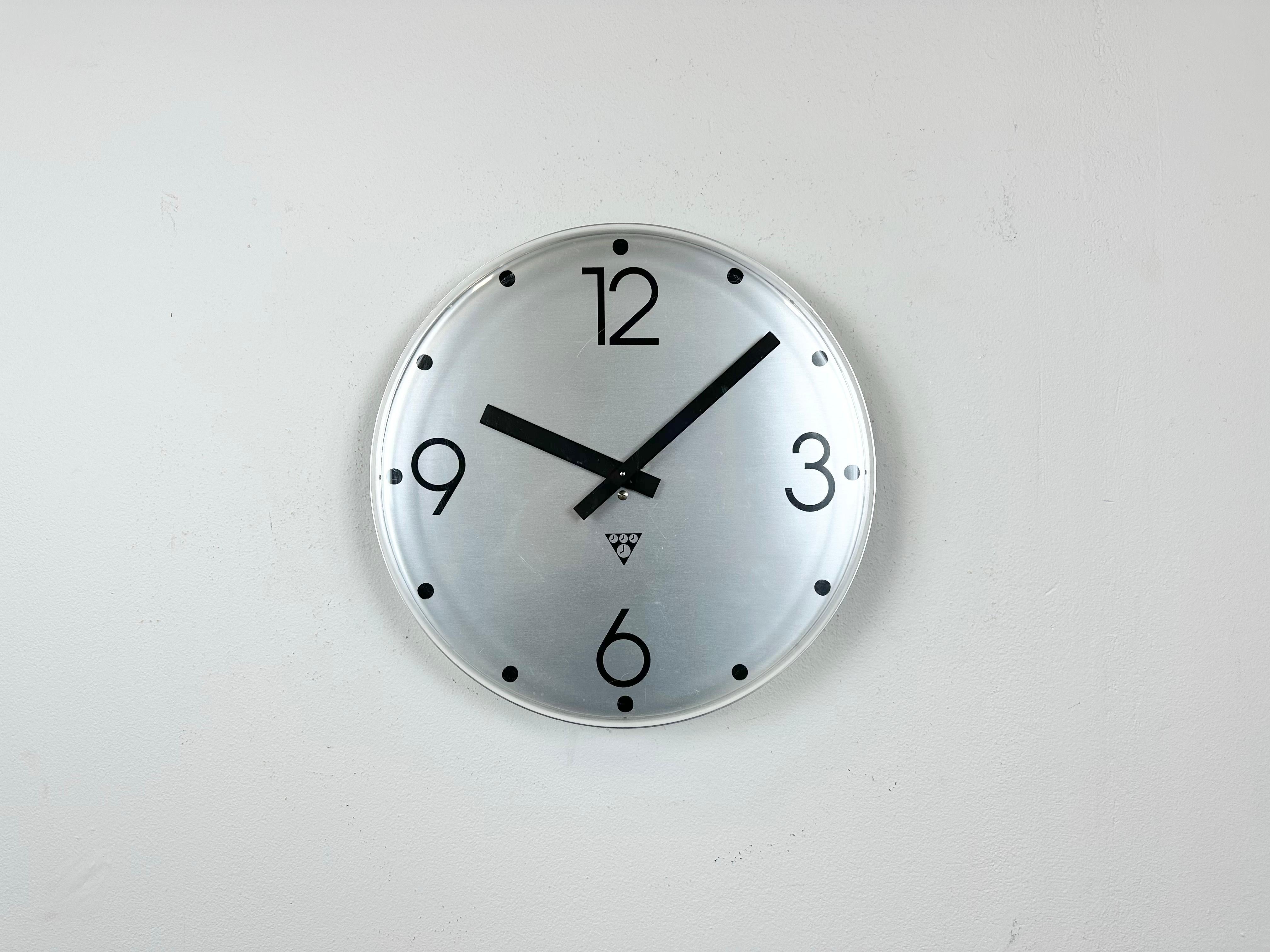 Industrial wall clock was produced by Pragotron in former Czechoslovakia during the 1980s. It features an aluminium dial and a curved plastic clear glass cover. The piece has been converted into a battery-powered clockwork and requires only one