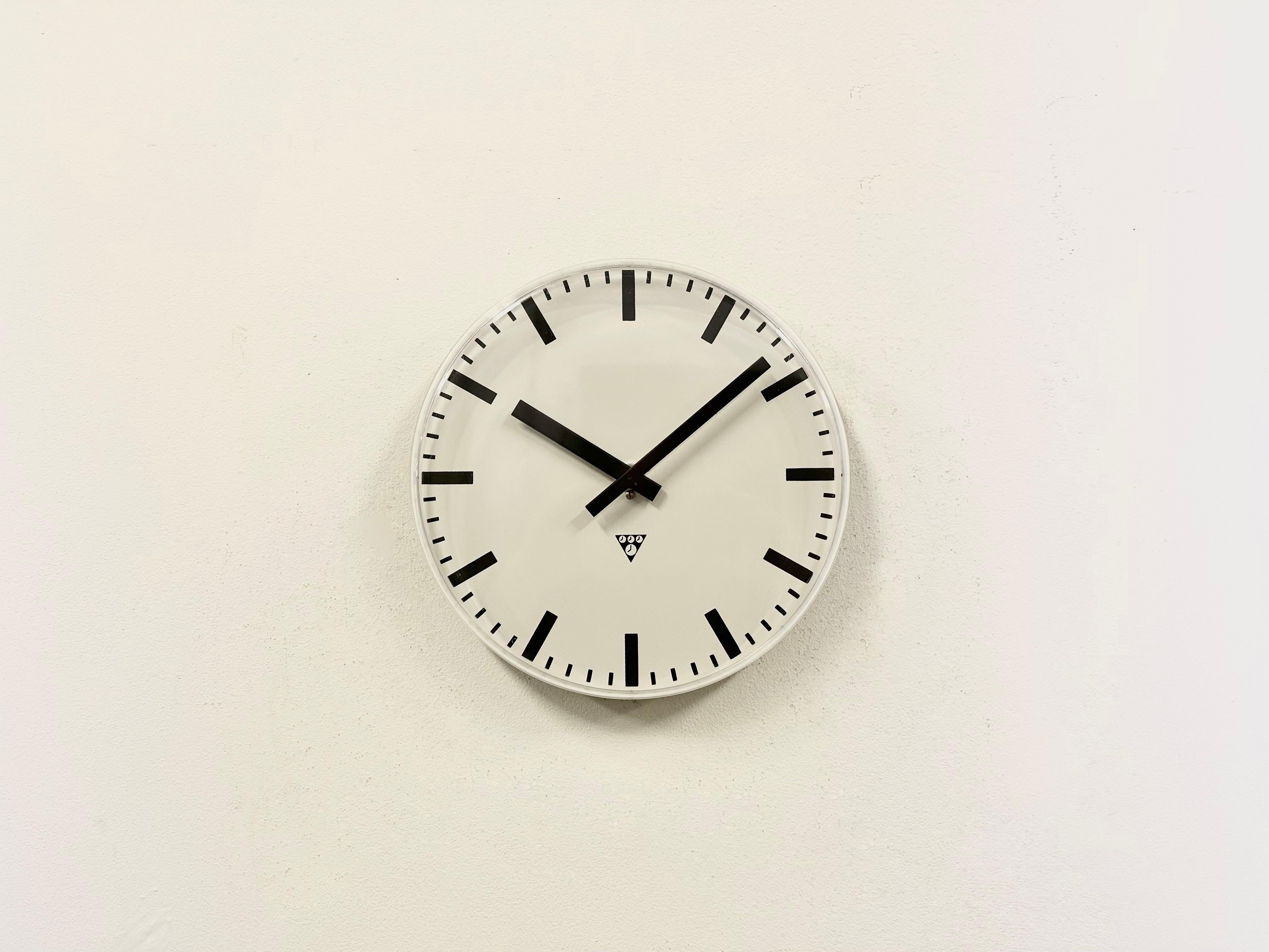 Industrial wall clock was produced by Pragotron in former Czechoslovakia during the 1980s. It features a white aluminium dial and a curved plastic glass cover. The piece has been converted into a battery-powered clockwork and requires only one