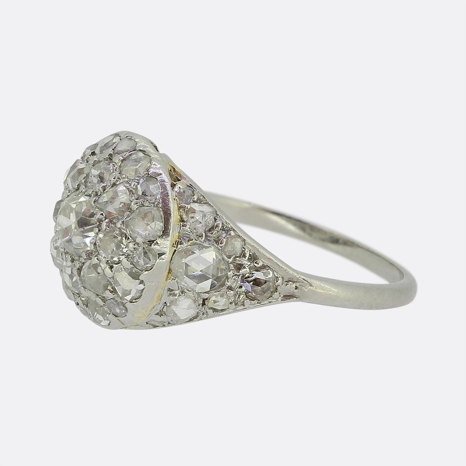 Here we have an exquisite diamond ring crafted from a blend of 18ct gold and platinum. At the centre, a prominent old mine-cut diamond radiates a captivating white hue. Surrounding this principal stone is a quartet of matching smaller stones at each