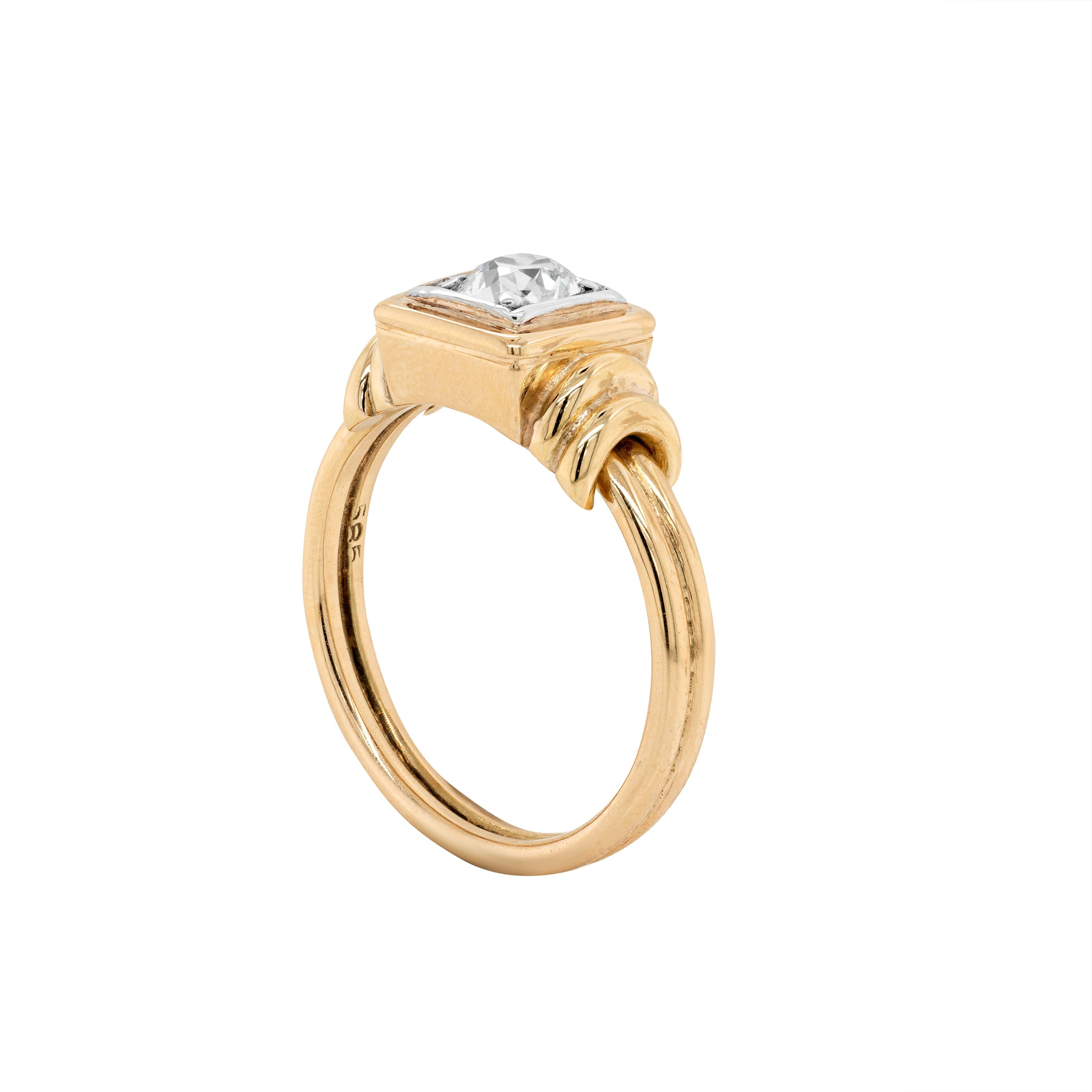 This gorgeous art deco style engagement ring features a beautiful old mine cut diamond weighing approximately 0.80ct, mounted in a 14 carat white and yellow gold square box setting. The piece is further decorated with yellow gold ring details