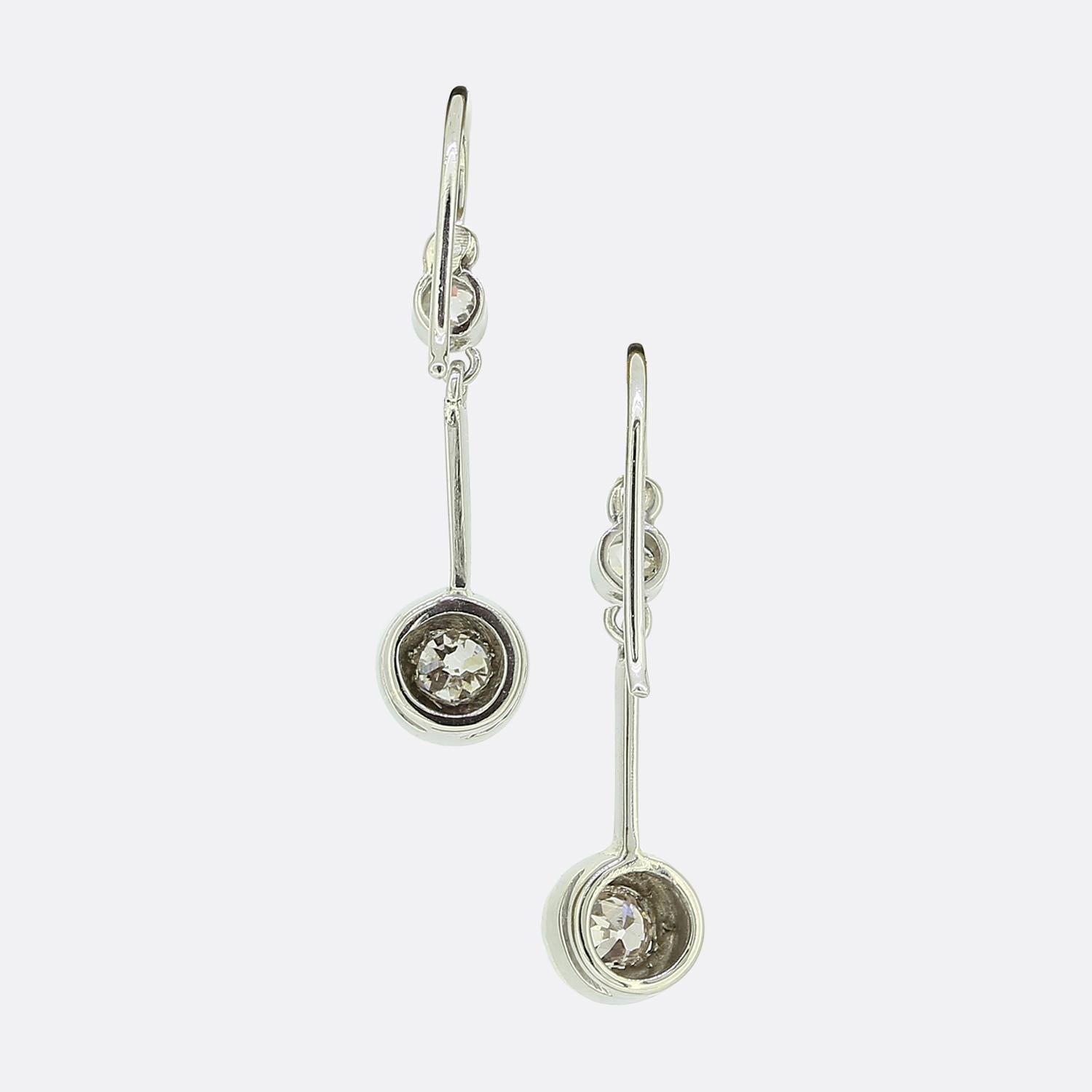 Here we have a beautifully crafted pair of diamond drop earrings. Each piece showcases a duo of round faceted old cut diamonds; the largest of which has been starburst set and freely suspended from its slightly smaller milgrain set counterpart