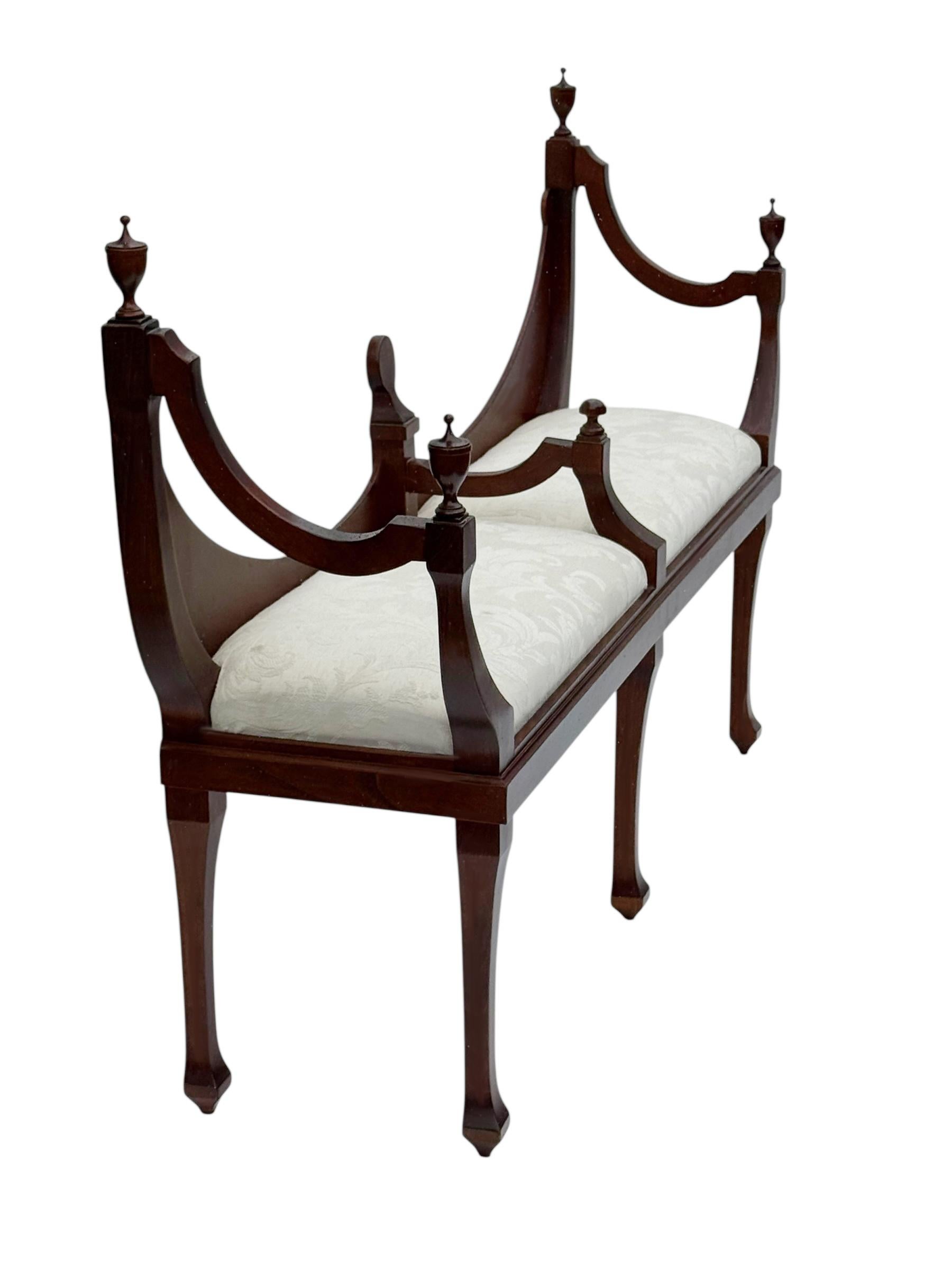 A highly decorative, classic Old English bench in mahogany with off white seat cushions. In great shape for it's age. 
